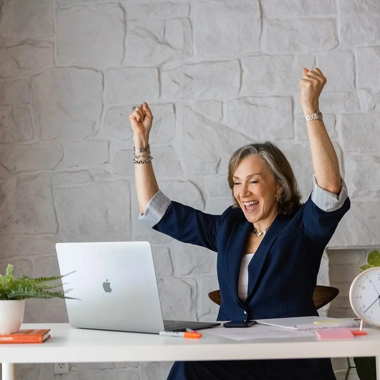 Studio business coach celebrating success at her laptop — the confidence and ease studio owners feel with the right support.
