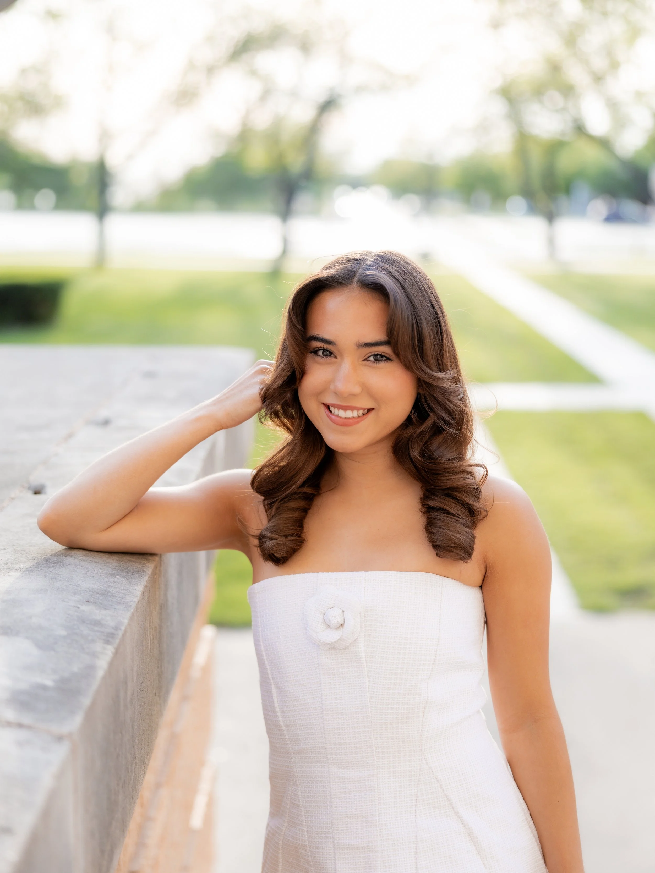 Woman in a white dress smiling outdoors during a portrait photography session.