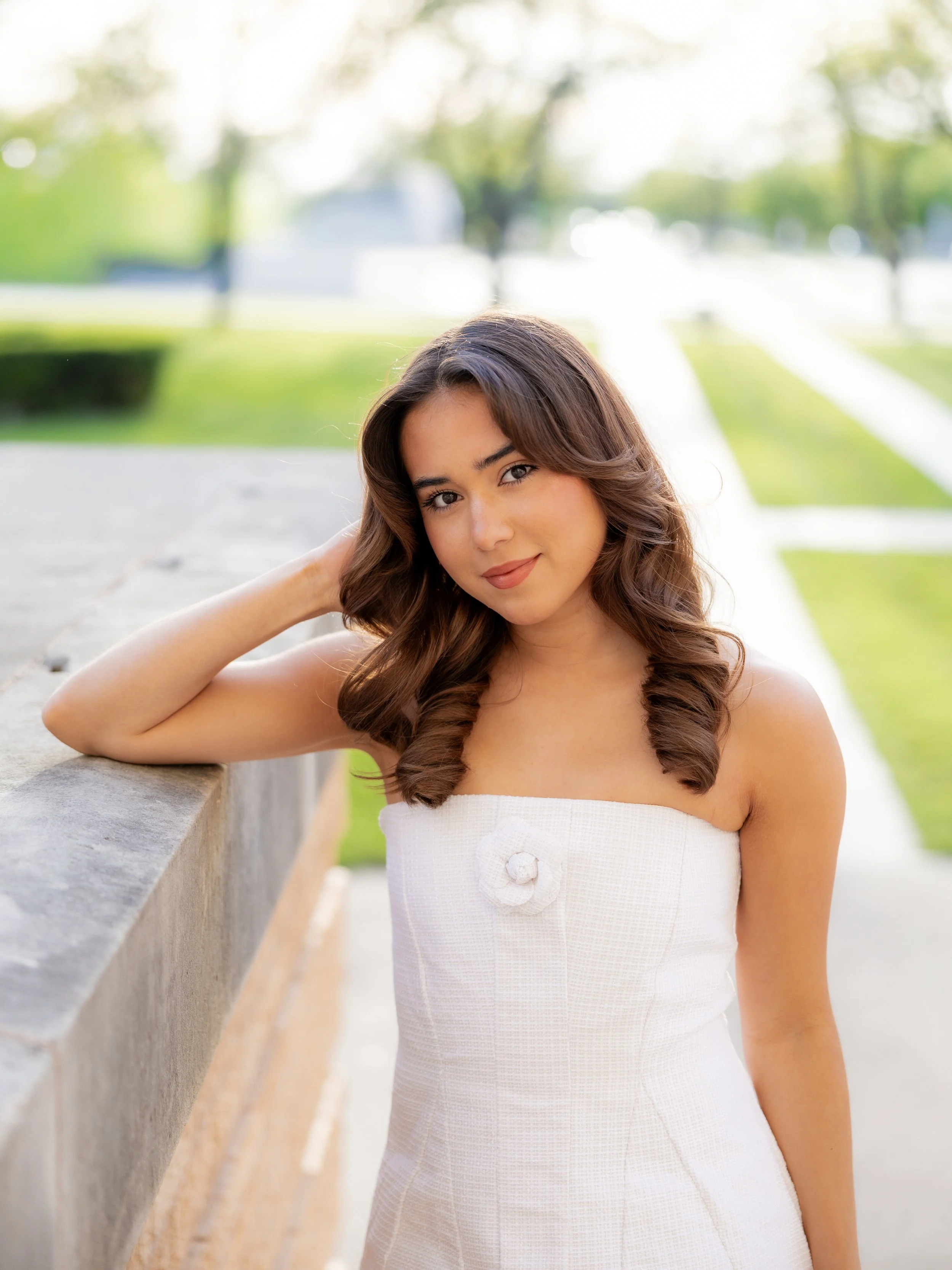 Woman posing outdoors in a white dress during a portrait photography session.