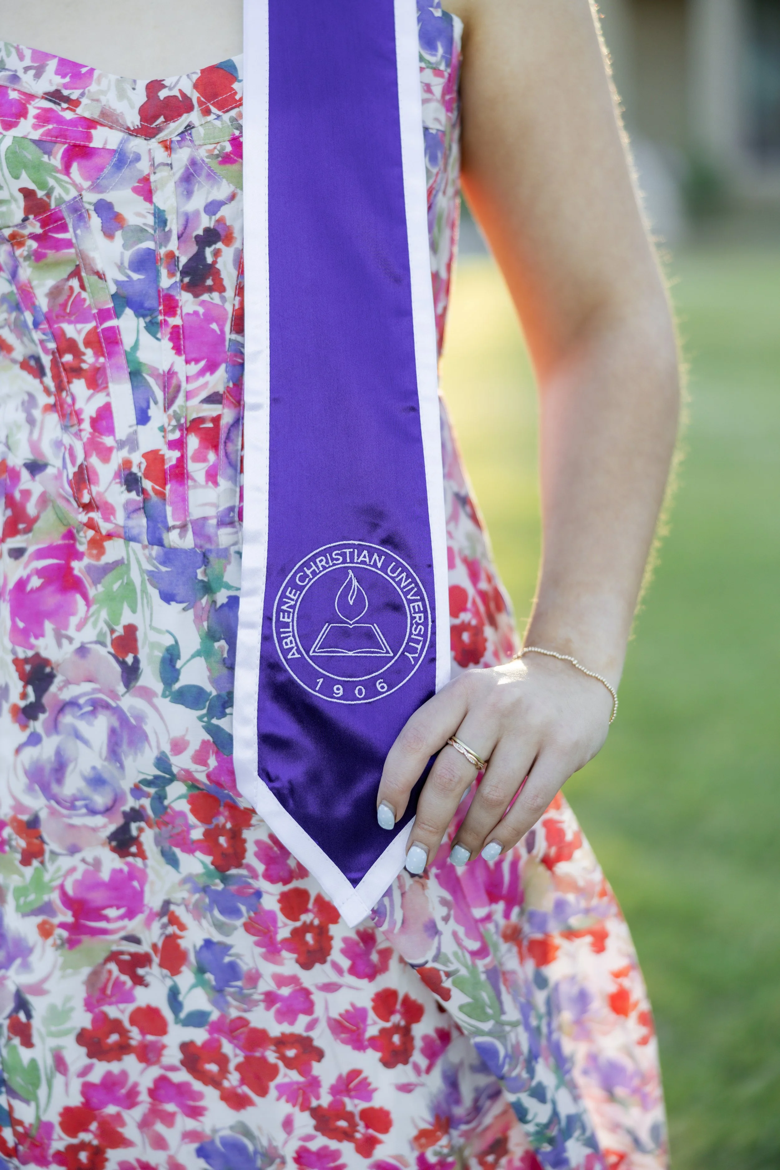 Close-up of a college graduate holding her purple graduation stole during a graduation portrait session.