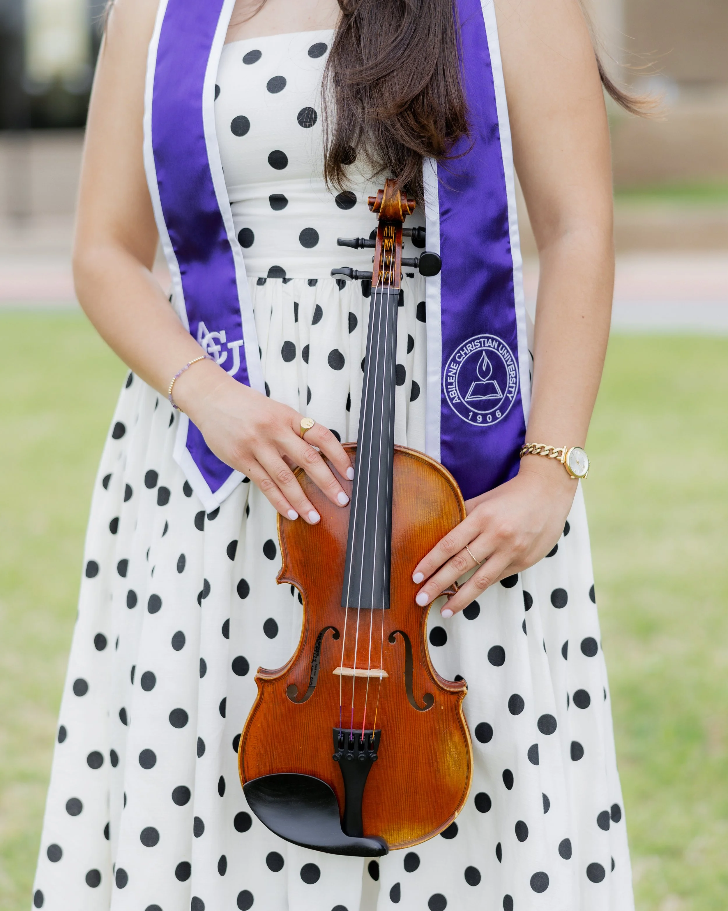 Abilene Christian University graduate holding her violin during a college graduation portrait session.