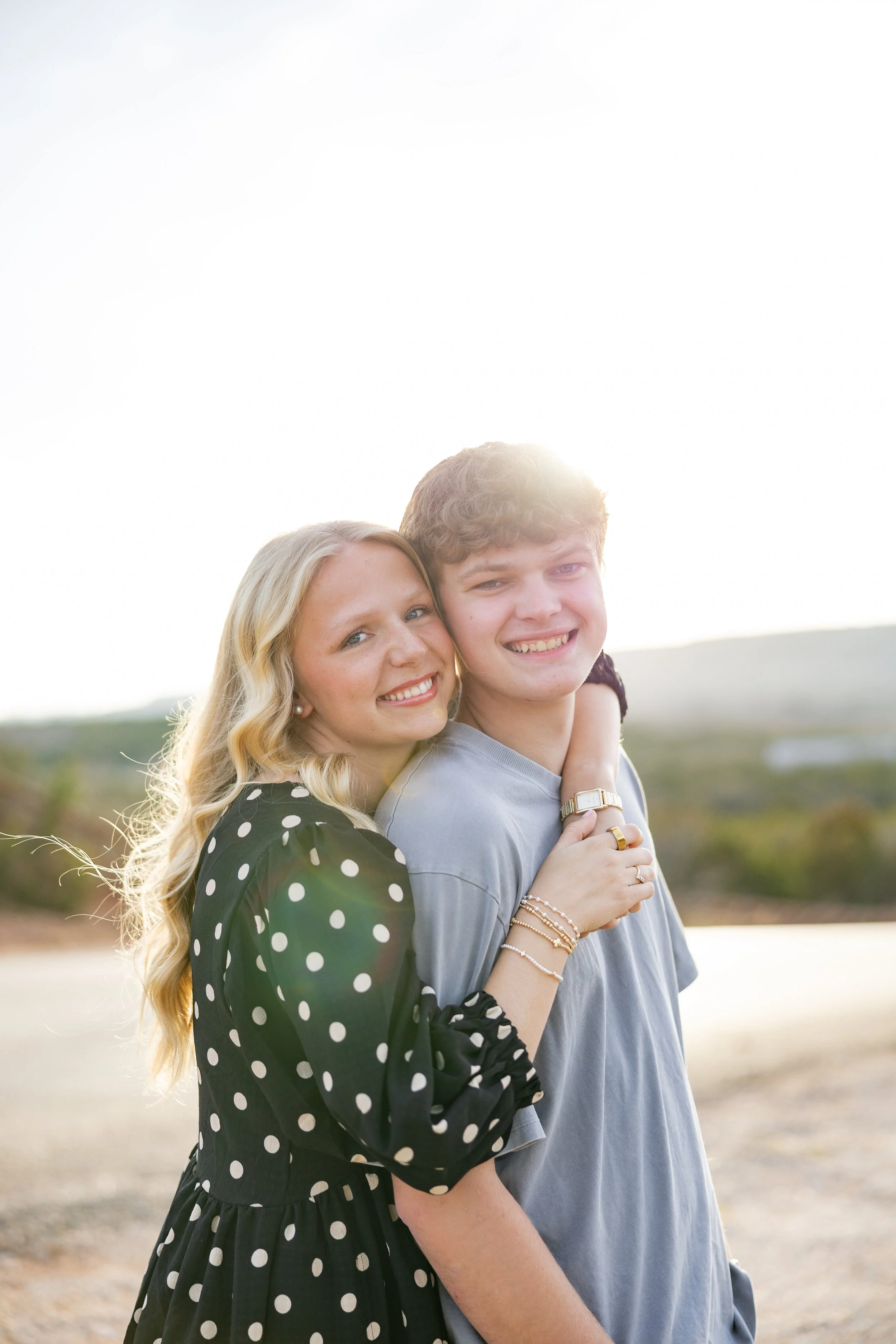 Couple hugging and smiling together during an outdoor engagement portrait session at sunset.