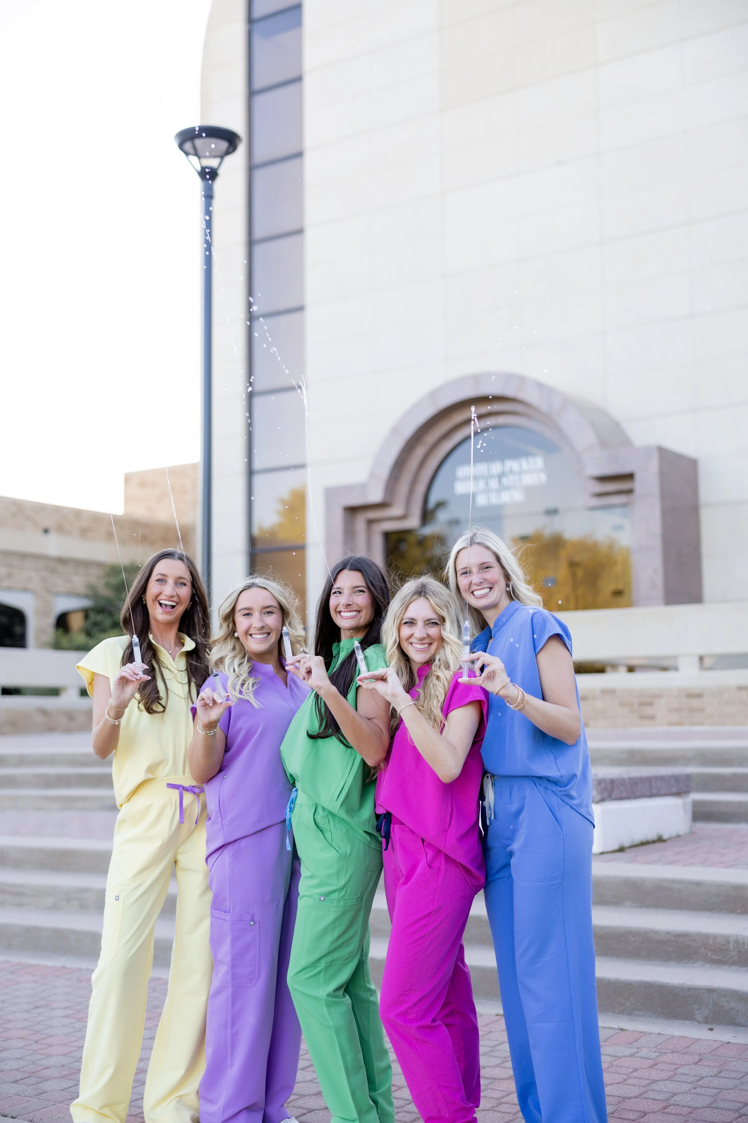Group of nursing graduates in colorful scrubs celebrating during a college group graduation session.