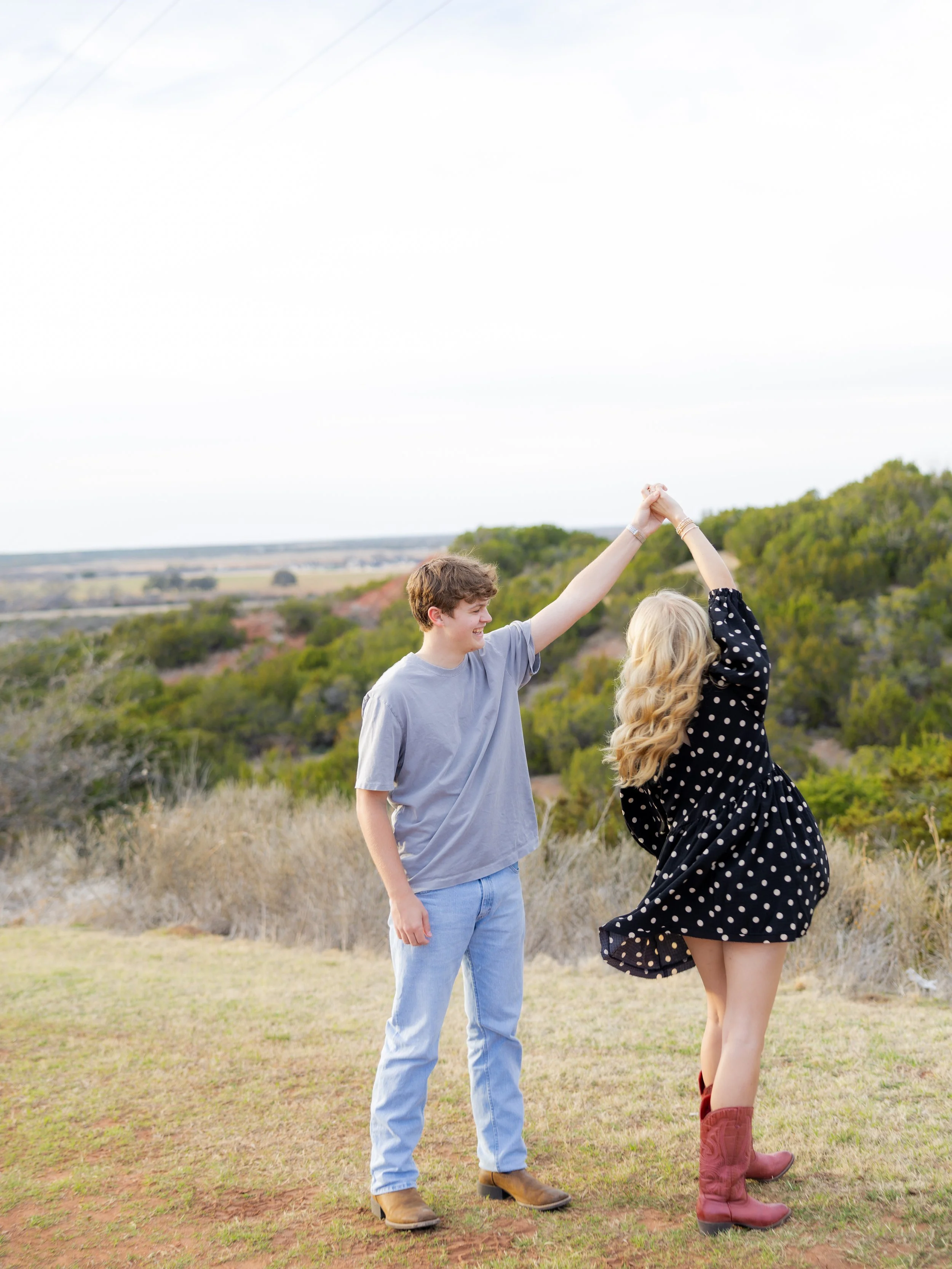 Couple dancing together in a grassy field during an outdoor couples photography session.
