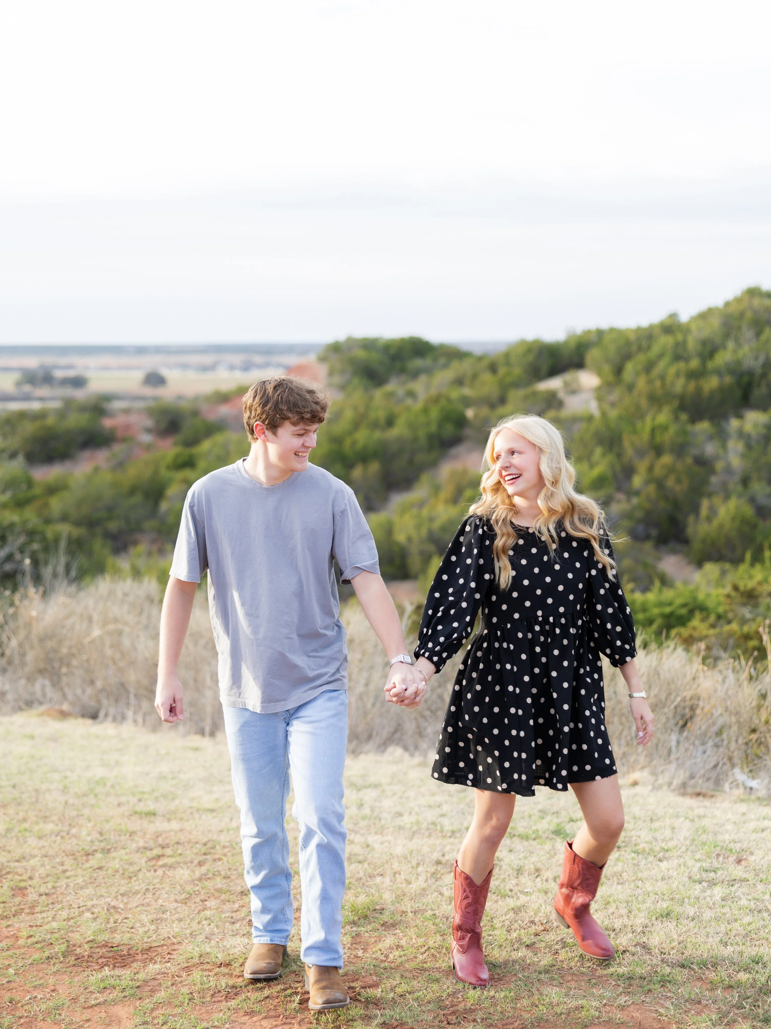 Couple holding hands and walking through a grassy field during an outdoor couples photography session.