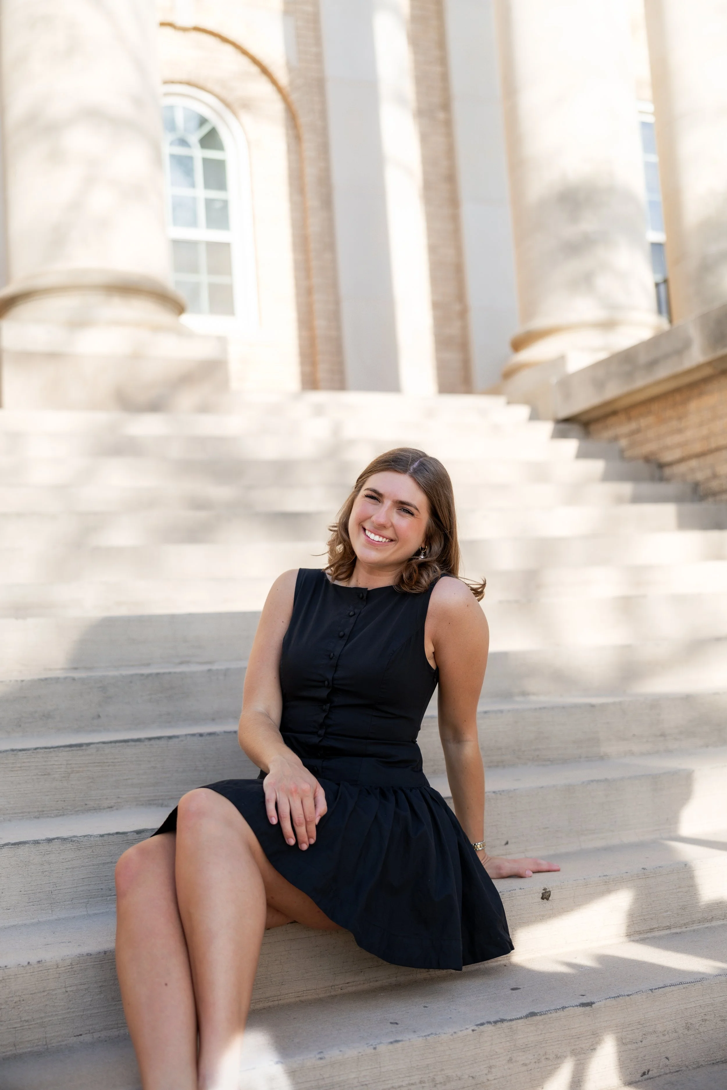 Woman posing outdoors in a black dress during a portrait photography session.