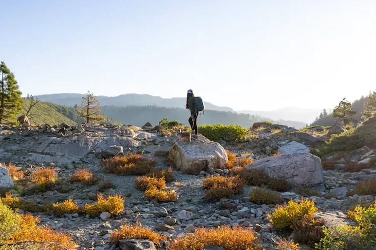 Hiker pausing on a granite overlook at golden hour, representing a new chapter and life transitions
