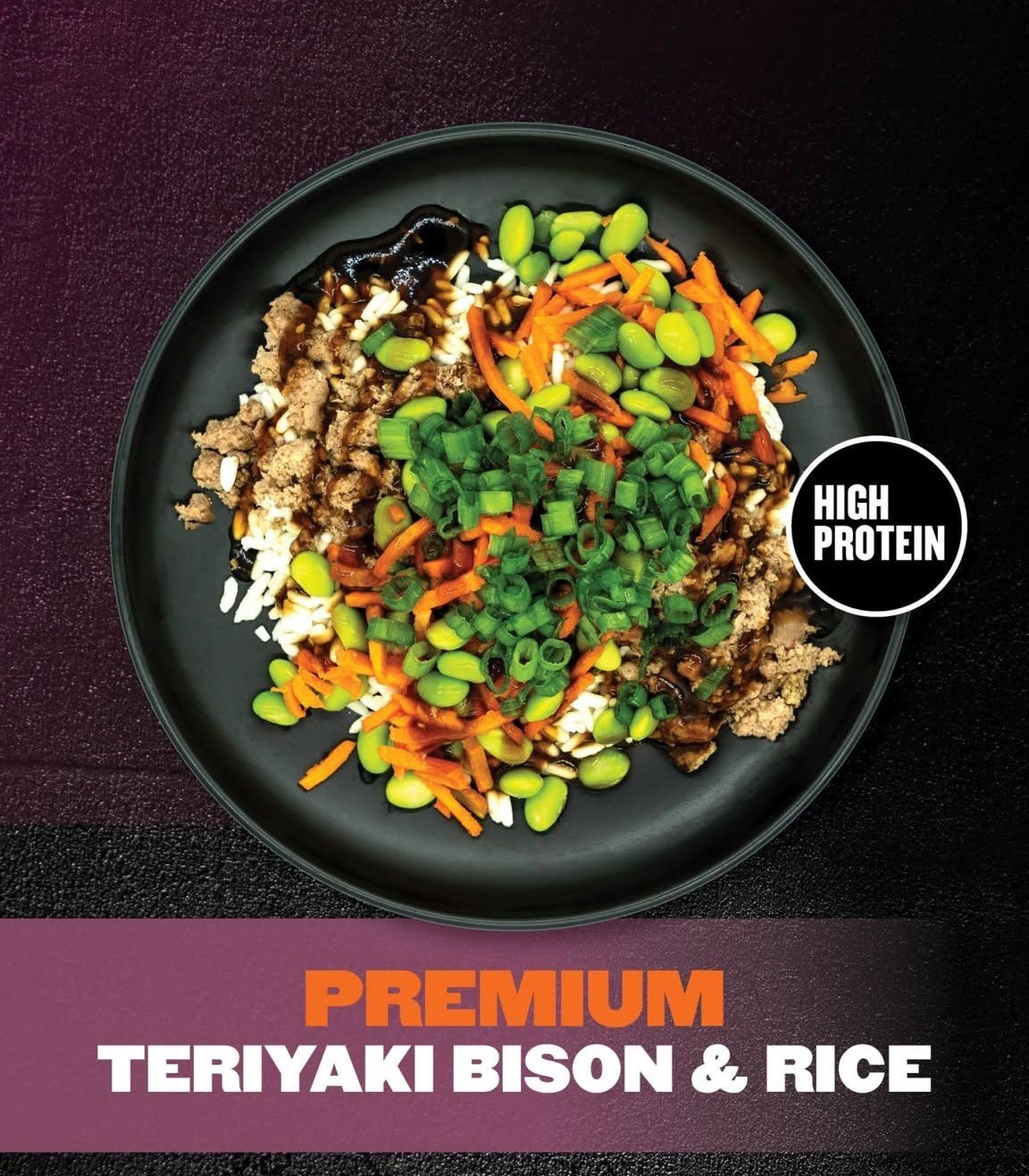 A plate of teriyaki bison with rice, topped with chopped green onions and shredded carrots, with a label indicating high protein content.