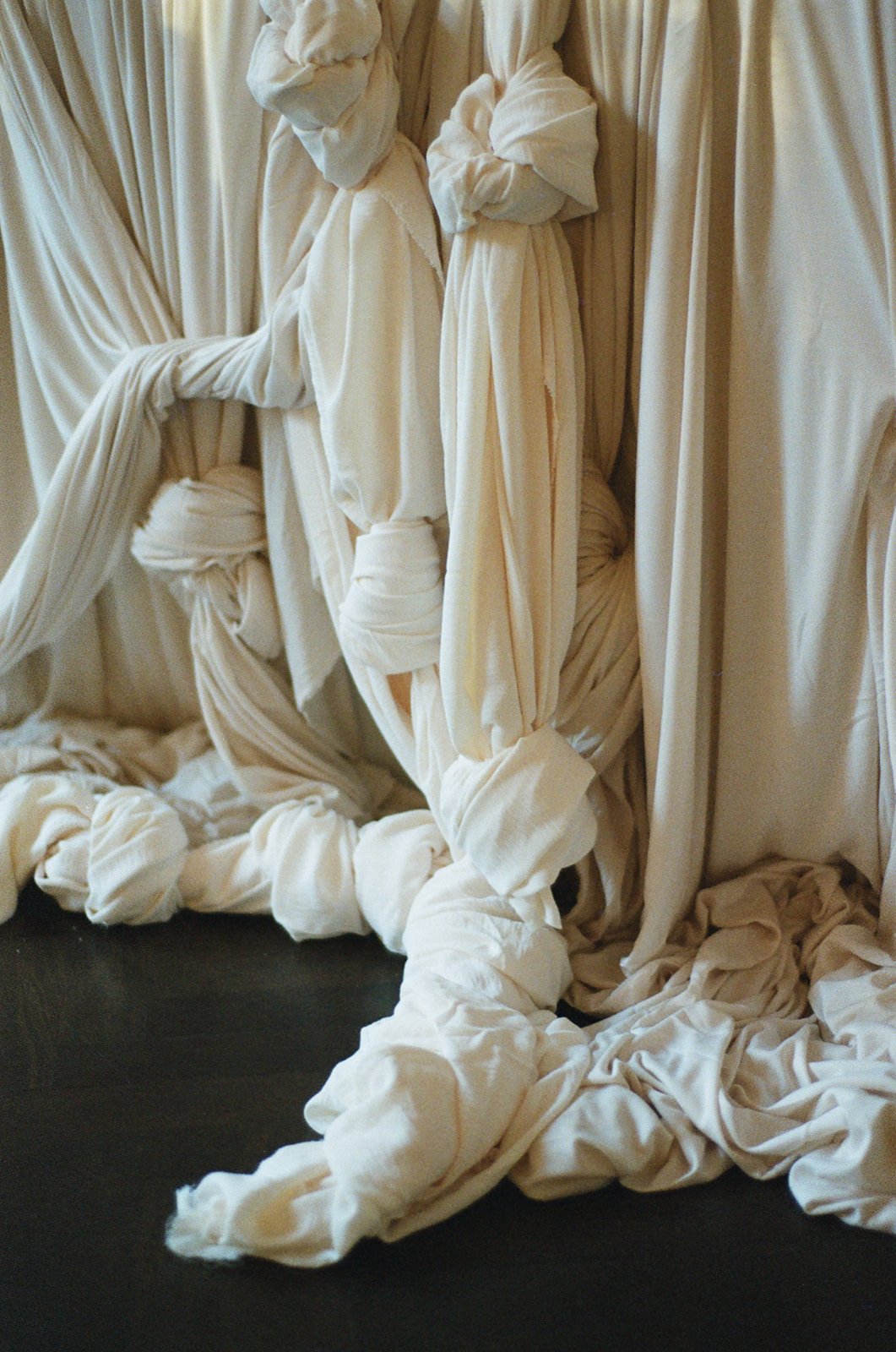 Tangled white fabric or sheets creating a chaotic scene with some draped and knotted sections.