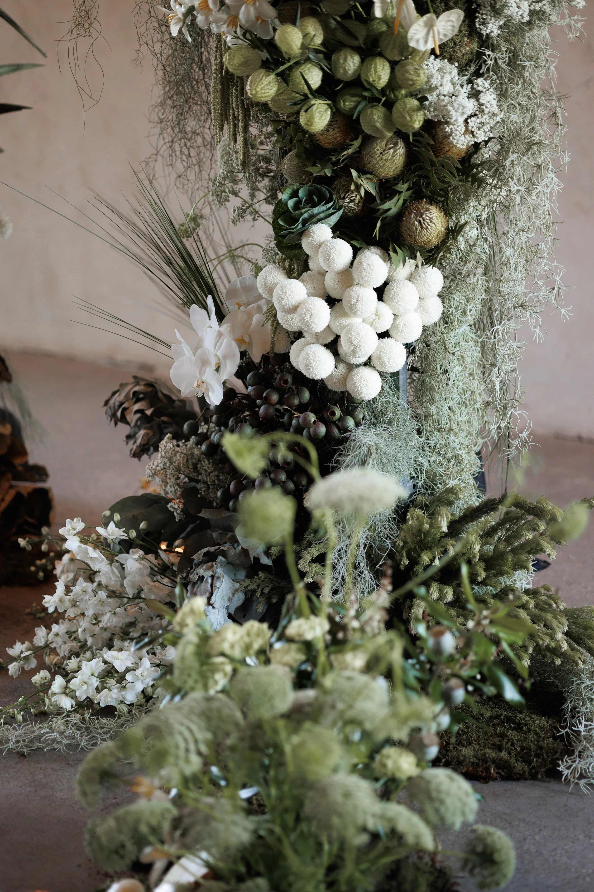 Arrangement of various white and green flowers, leaves, and foliage in a lush, textured display.