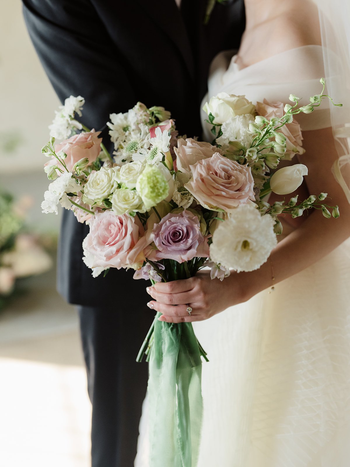 A bride holding a bouquet of pink, white, and lavender flowers at a wedding ceremony.