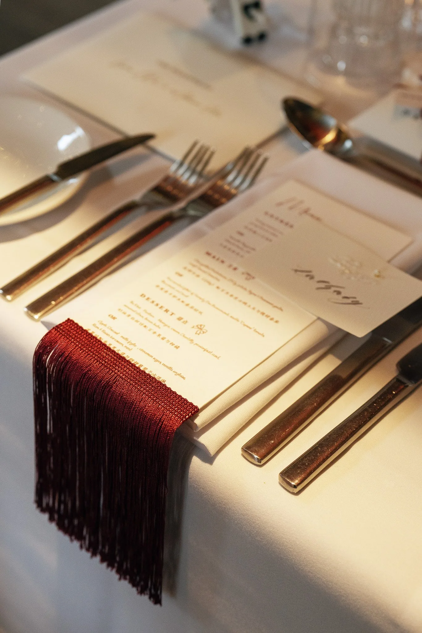 Table setting with cutlery, a menu, and a white tablecloth at a restaurant.