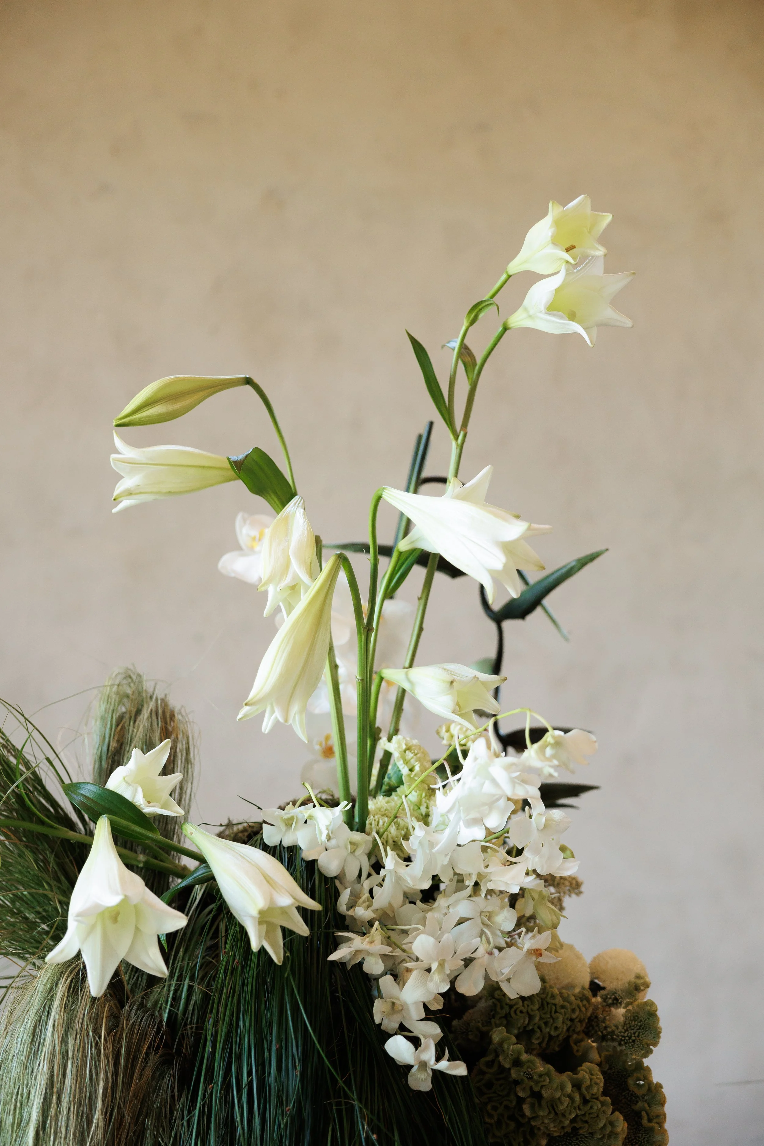 Arrangement of white lilies, hydrangeas, and greenery in a floral display.