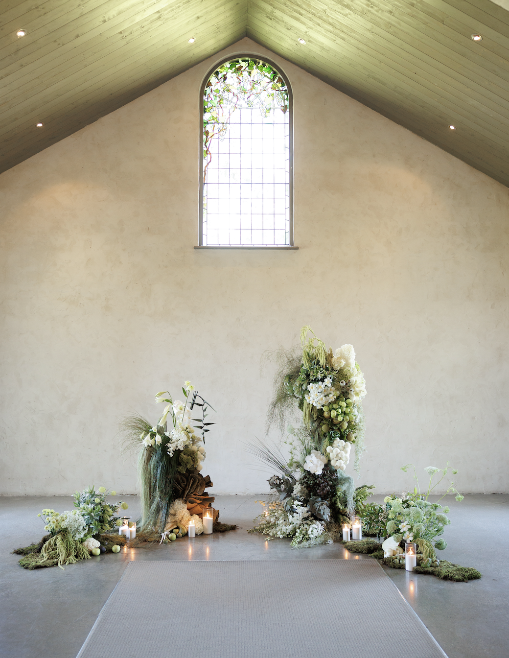 Wedding ceremony altar with floral arrangements and candles in a minimalist church interior.