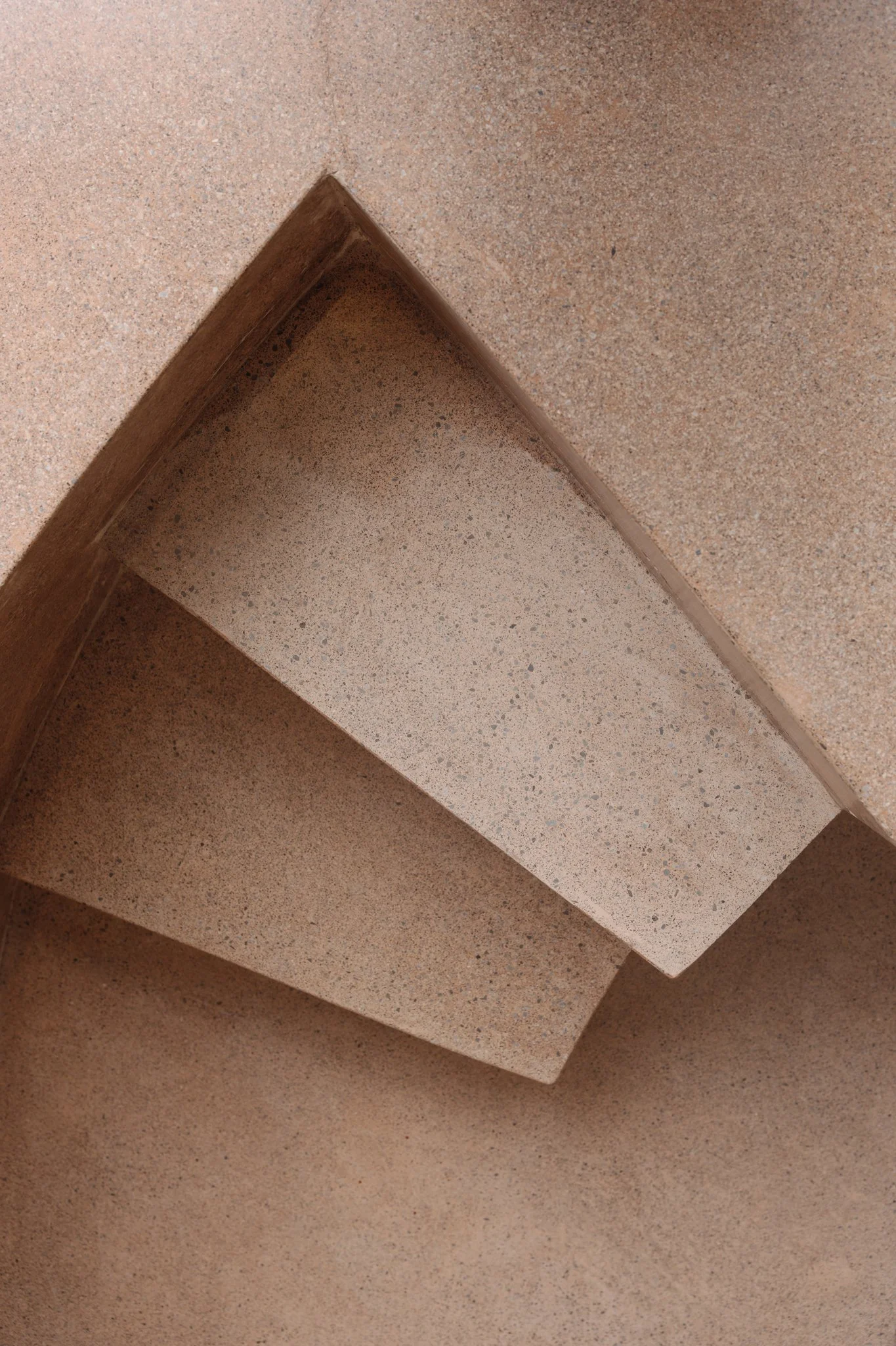 Close-up of a beige and brown terrazzo staircase with wooden edge trim.