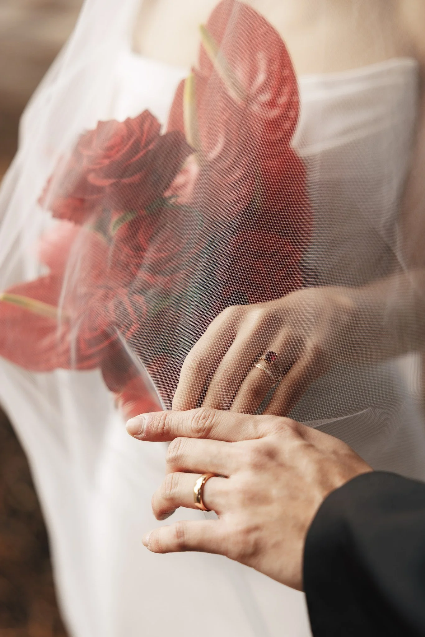 A person placing a bouquet of red roses wrapped in white paper into a person's hand.
