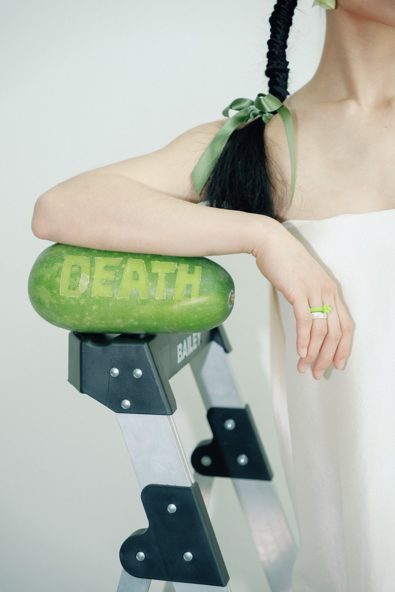 A person's arm resting on a green exercise balance board with the word 'DEATH' carved into it, mounted on a black and silver exercise machine.