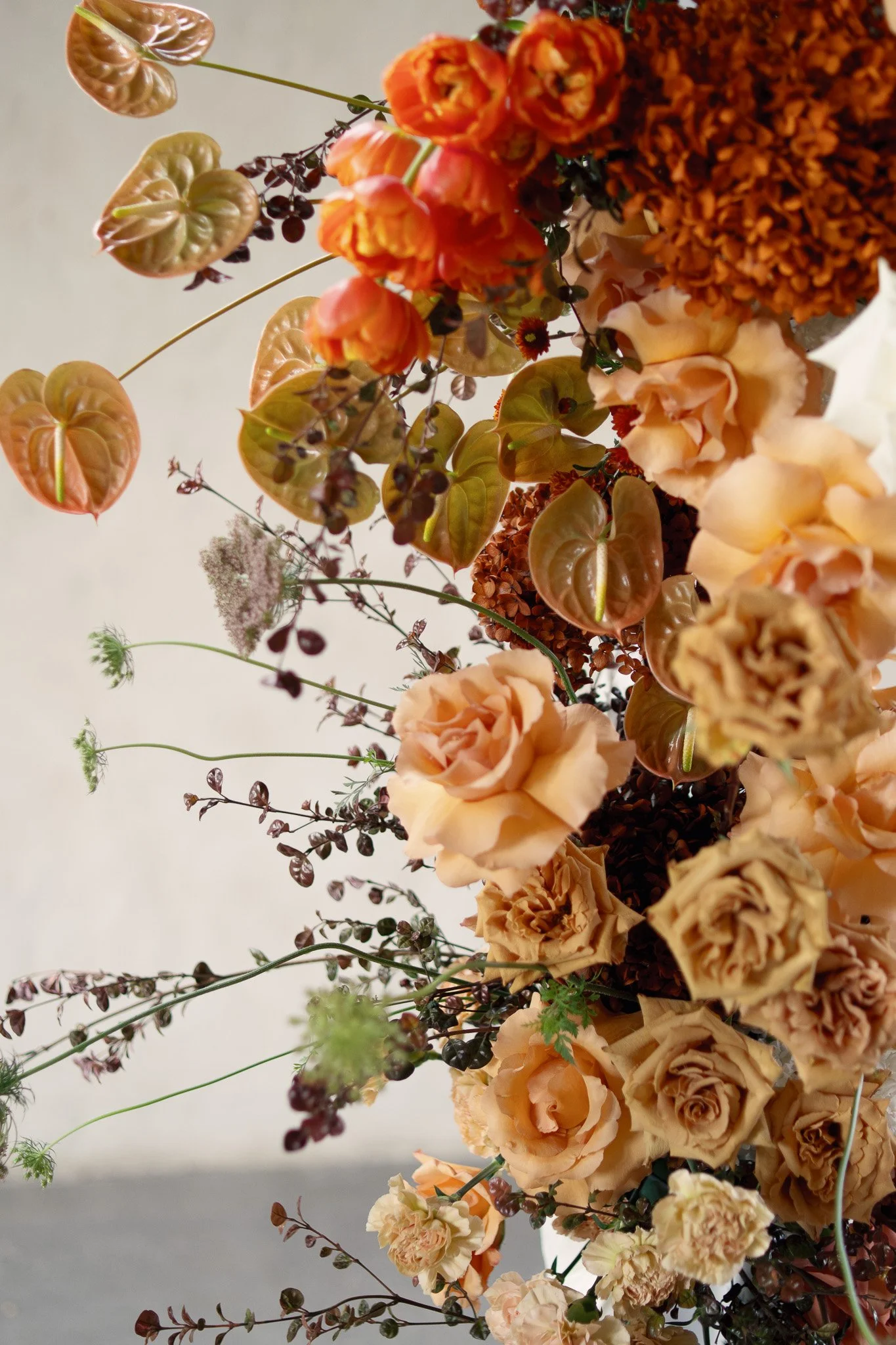 A close-up of a floral arrangement with peach, orange, and cream-colored roses, along with other small flowers and foliage.