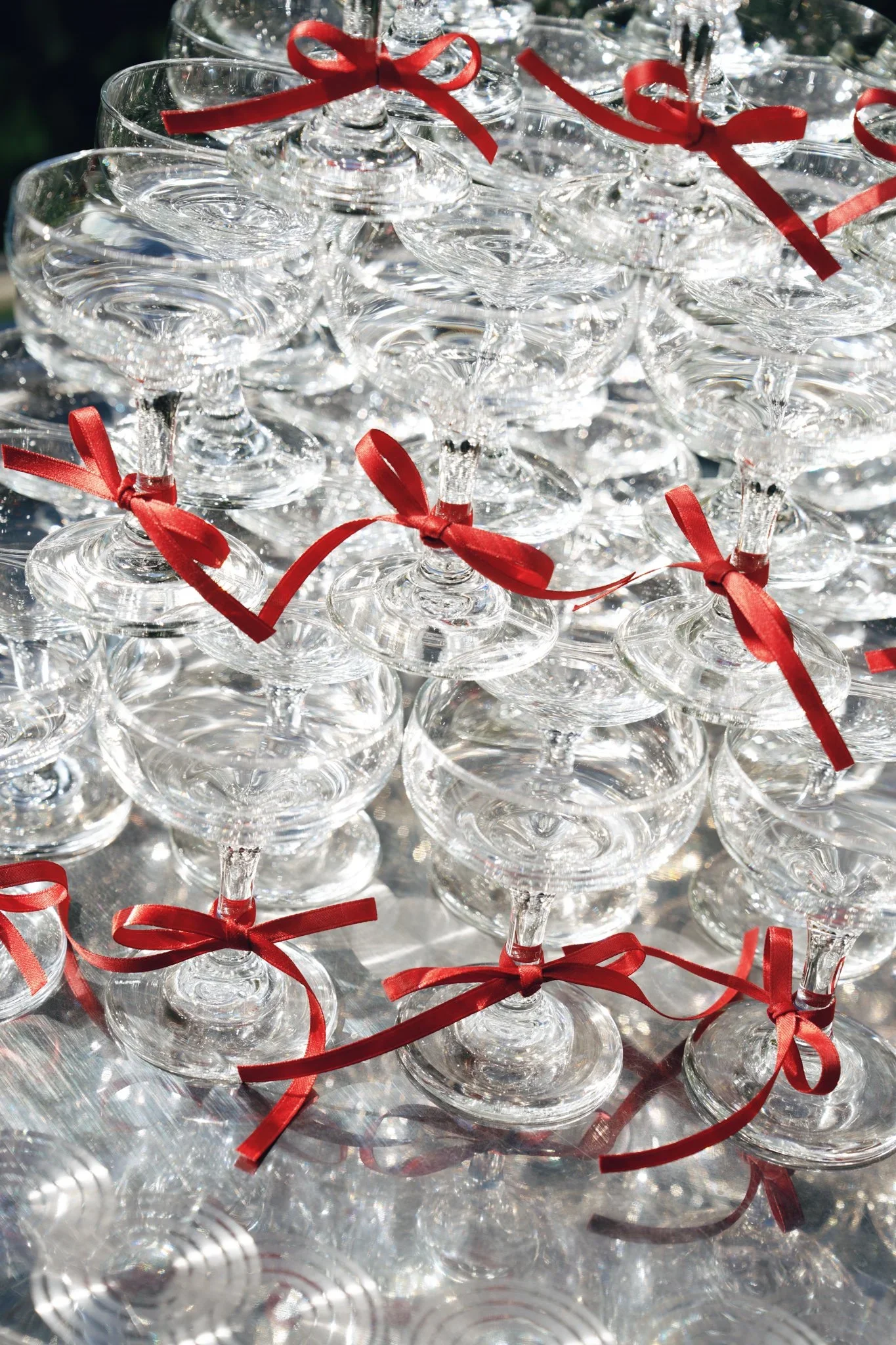 A close-up view of multiple empty champagne glasses decorated with red ribbons, arranged in a pyramid or stack for a celebration or event.