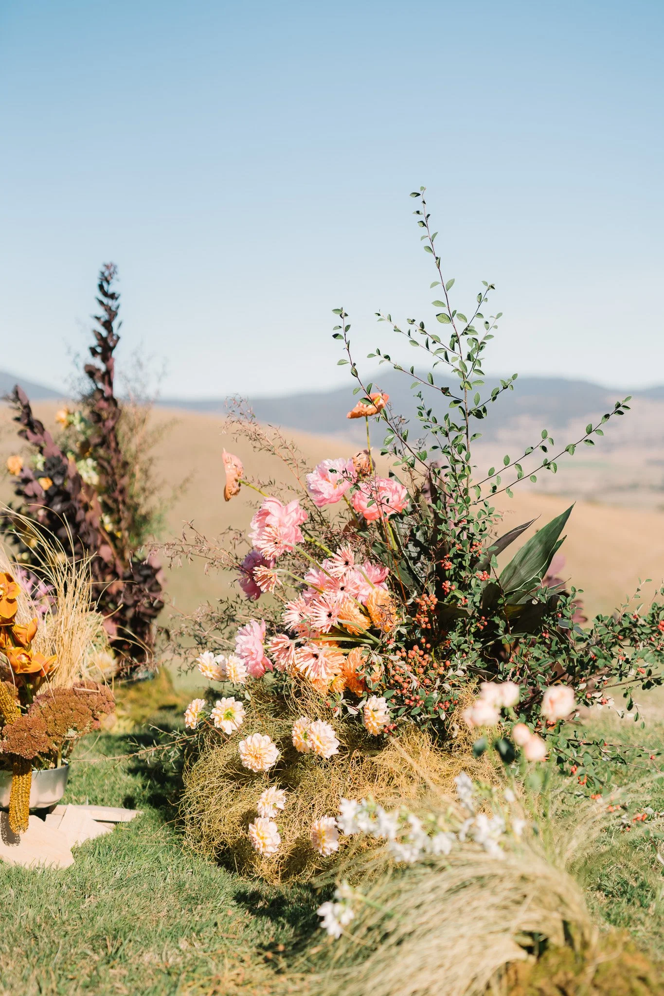 Arrangement of pink, peach, and white flowers with greenery and desert landscape background