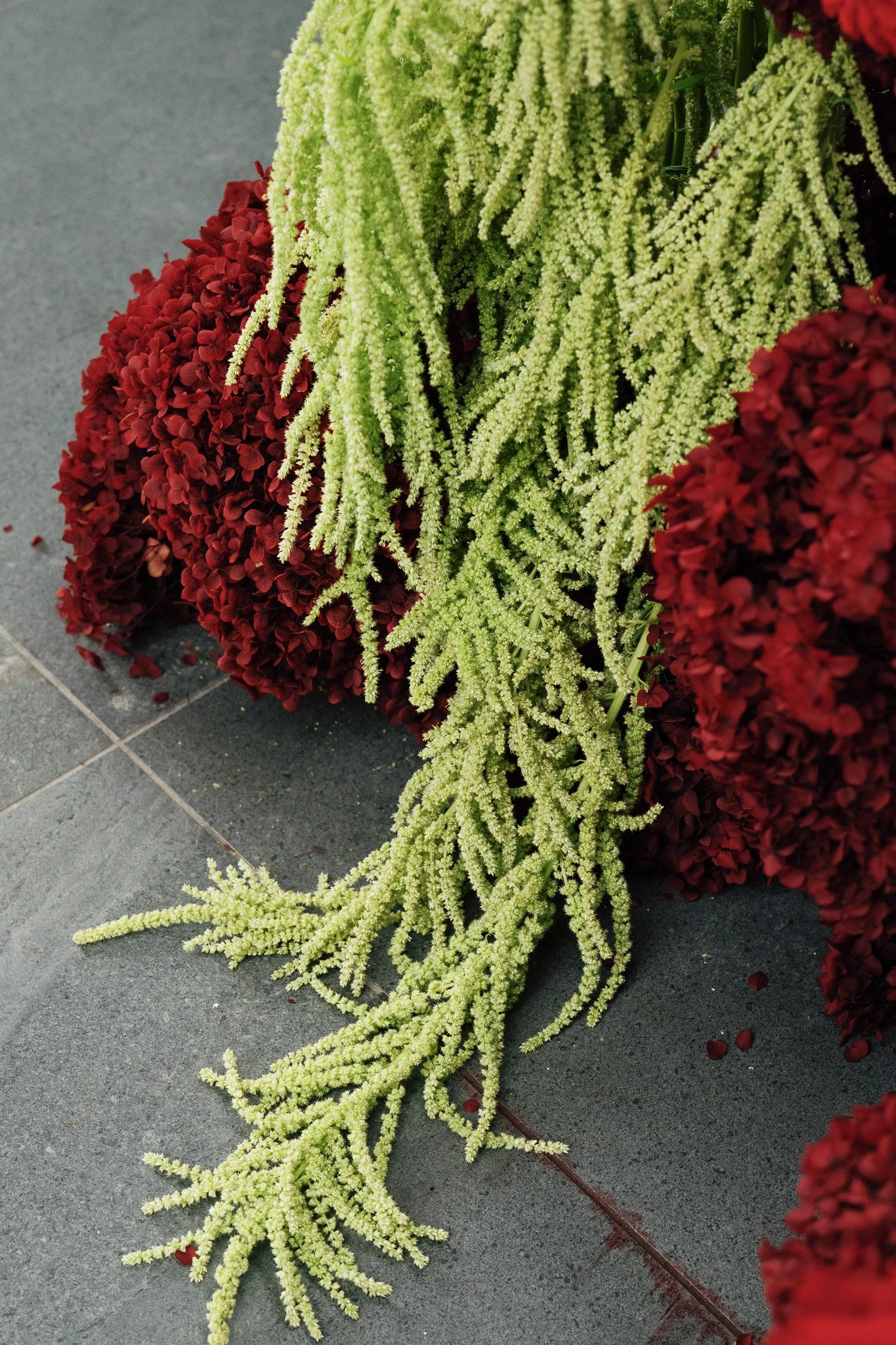Yellow and red funeral flowers assembled on gray tile flooring.