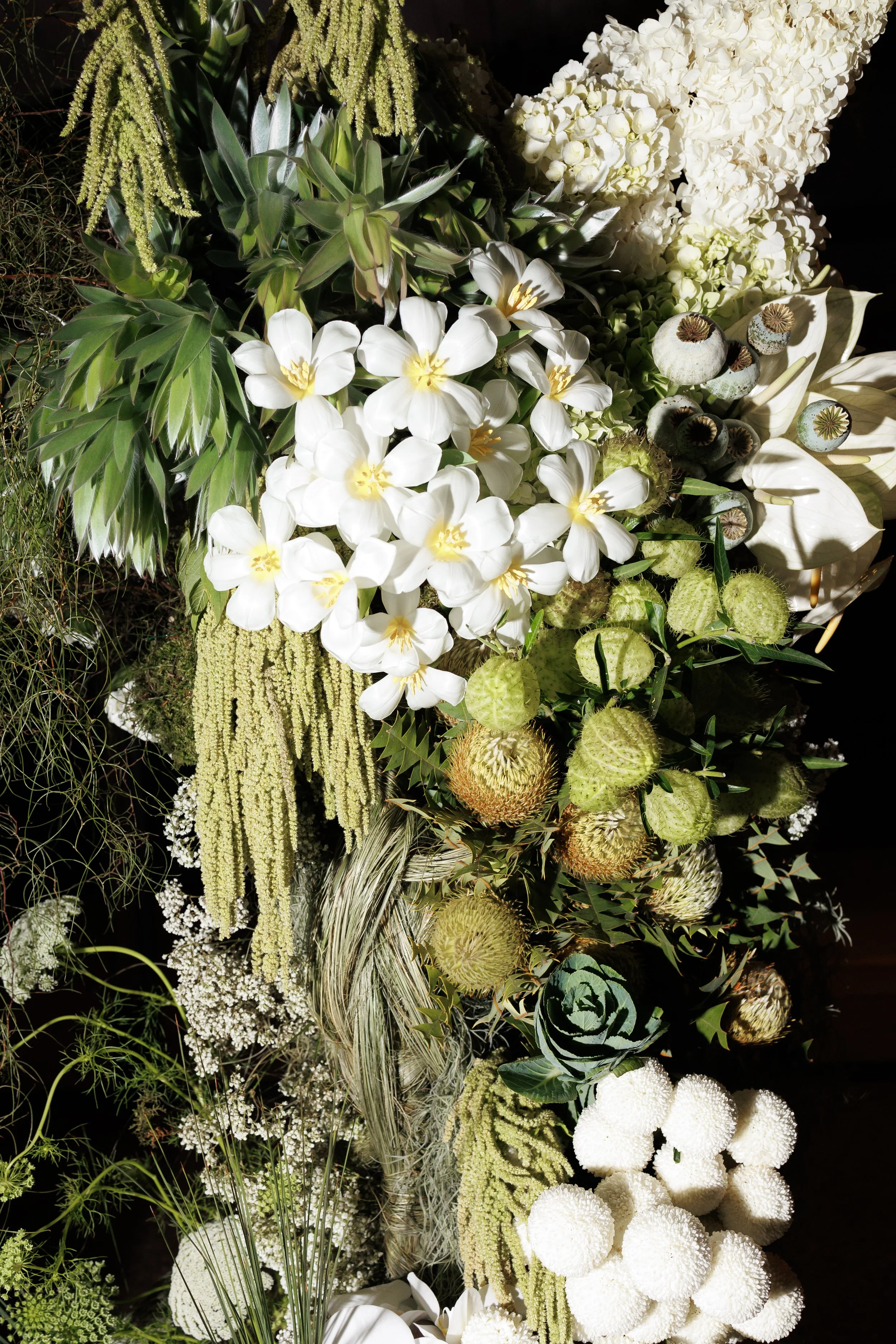 Arrangement of white and green flowers, including orchids, hydrangeas, poppies, and various greenery.