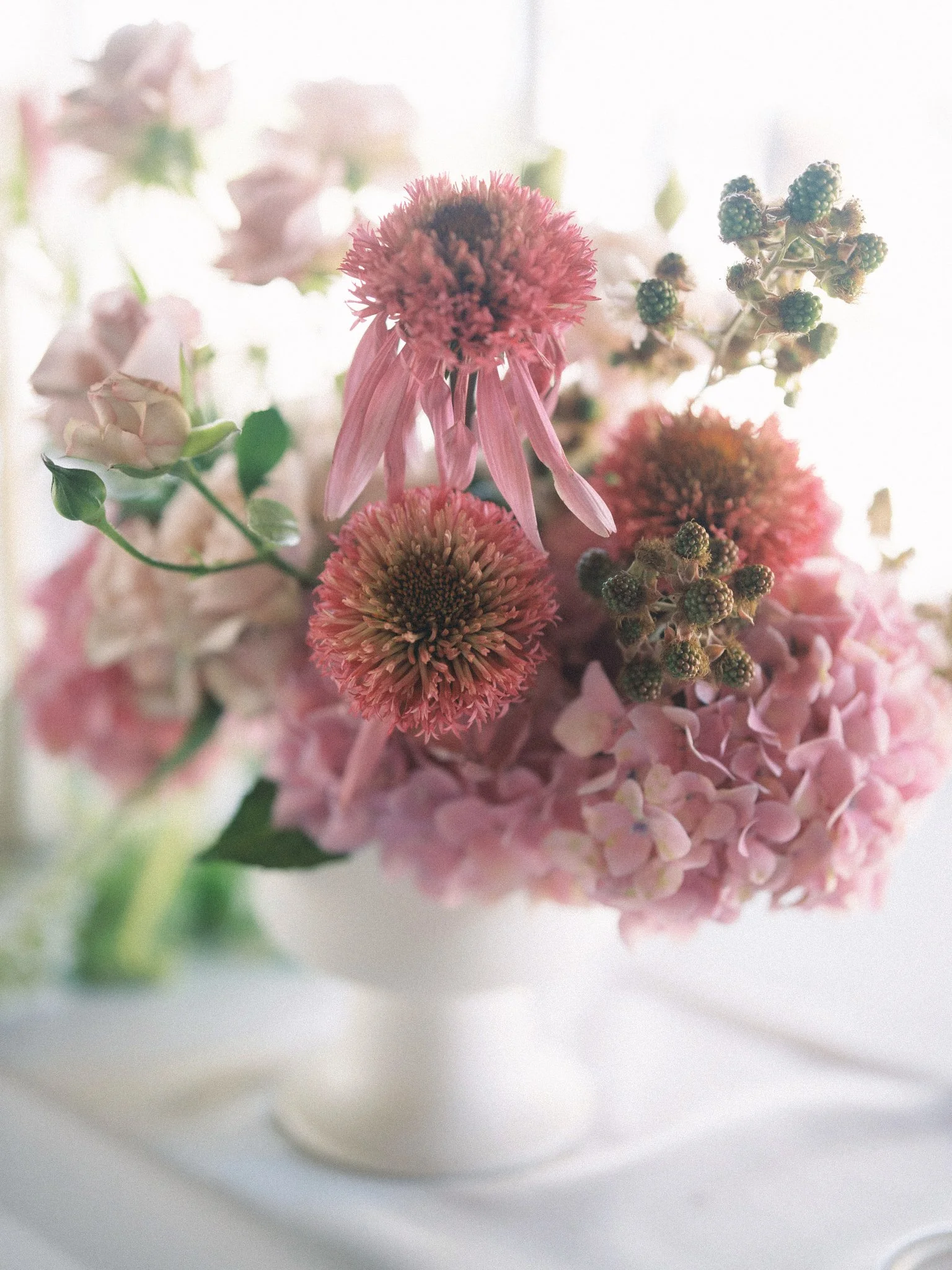 A floral arrangement with pink, purple, and white flowers on a white background.