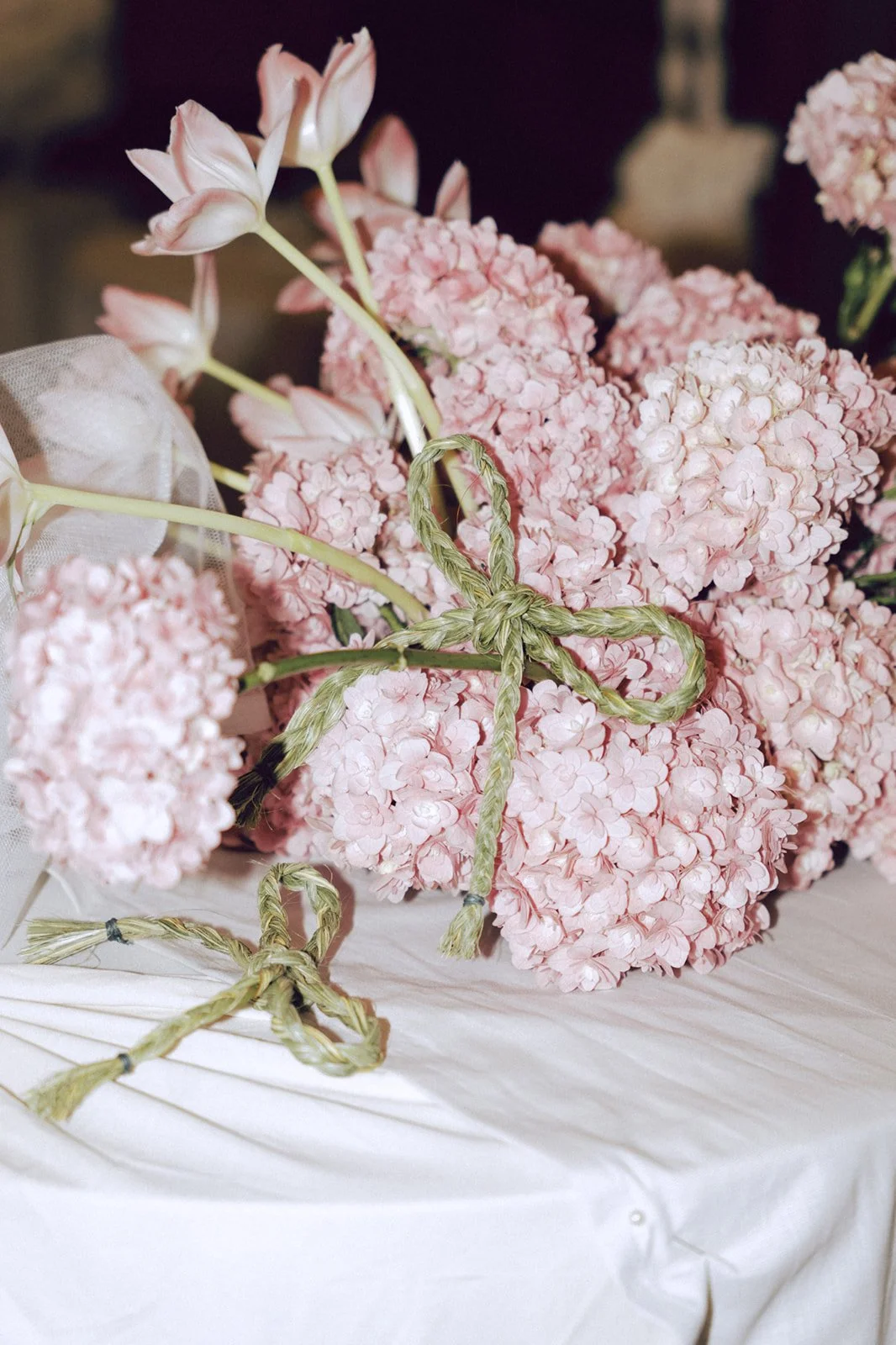 A bouquet of pink hydrangeas and lilies tied with green raffia.