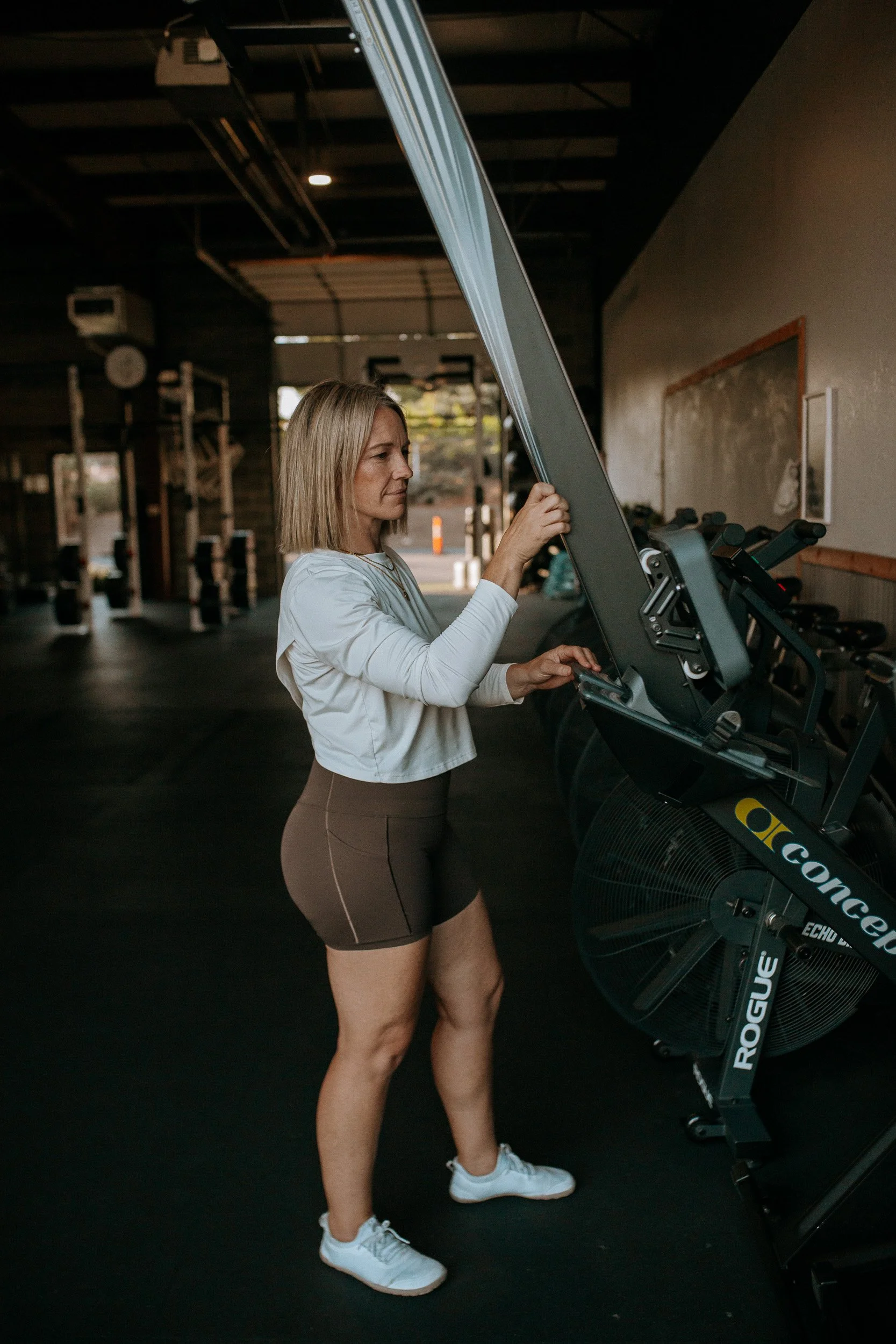 Coach Lu Crenshaw of Dropgym in Medford ,Oregon is lowering a row machine in their wharehouse gym.