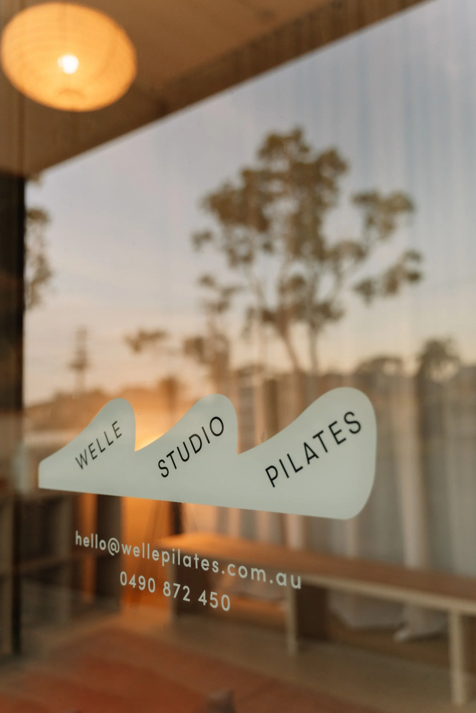 Welle Pilates studio branding and window signage