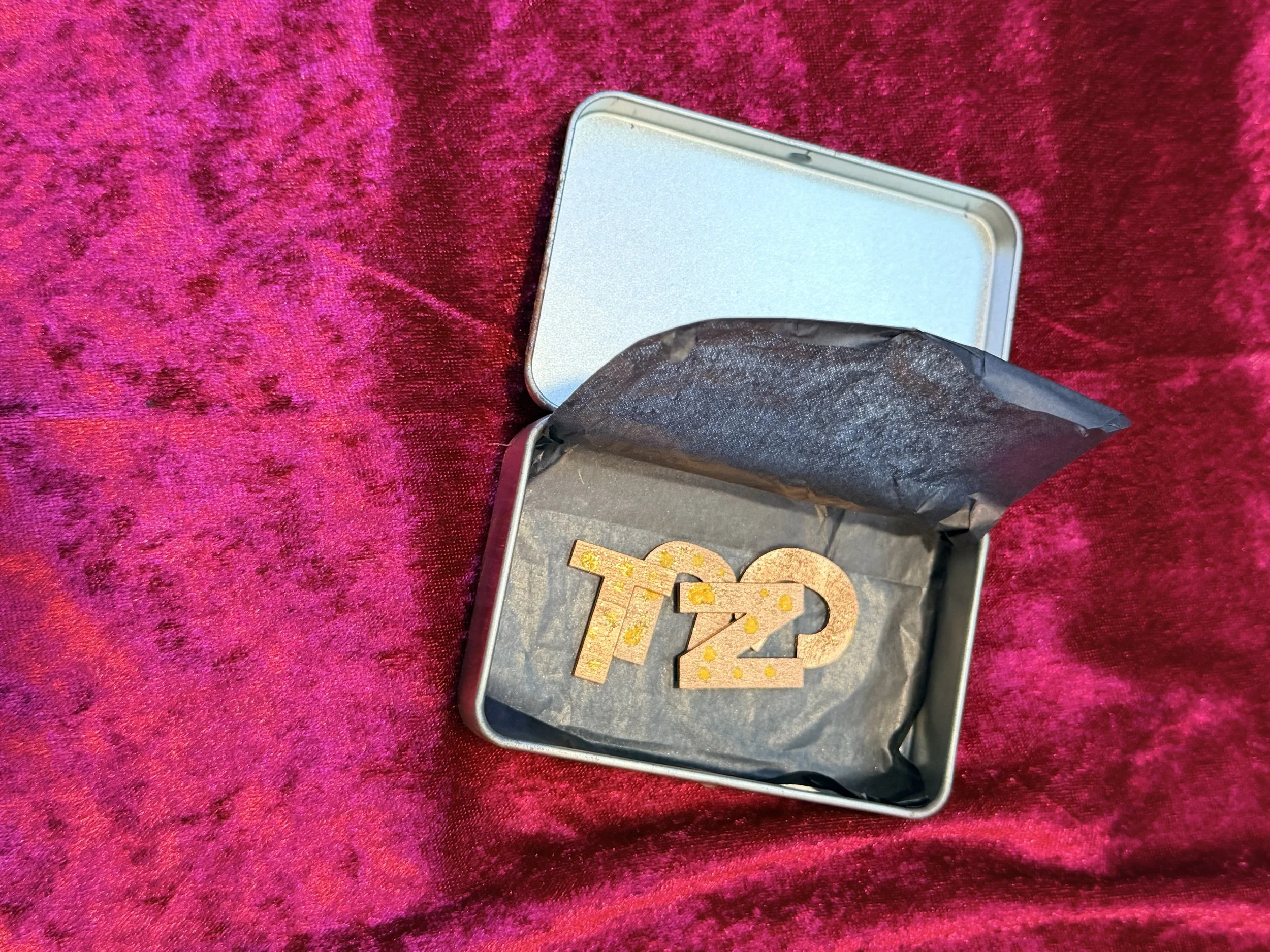 Image of a decorated rectangular box with the word 'LOVE' inside, resting on a pink textured fabric background.