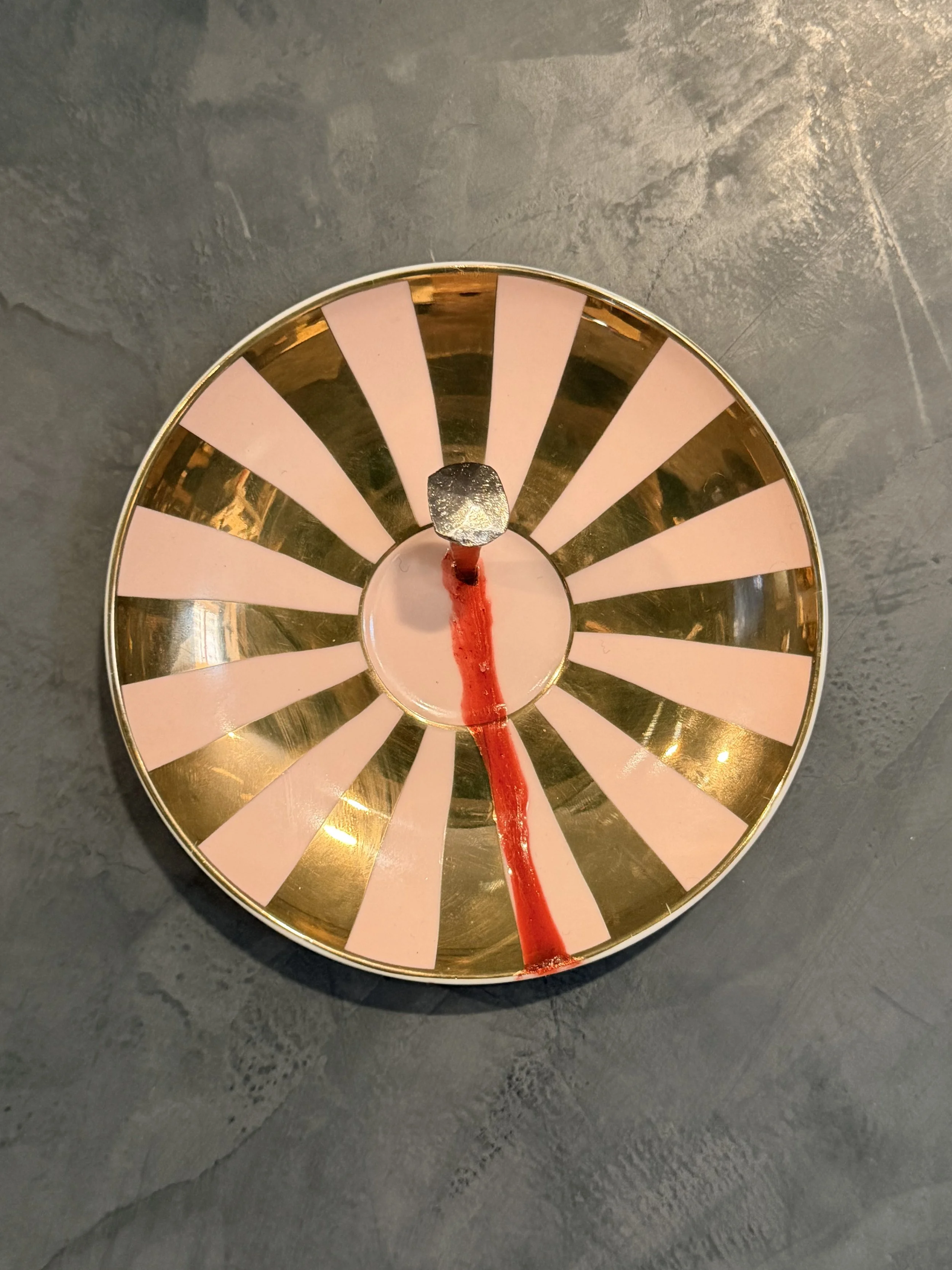 A decorative round tray with black and pink alternating stripes on the inside, a metal rim, and a red ribbon or string inside the tray laying along the bottom.