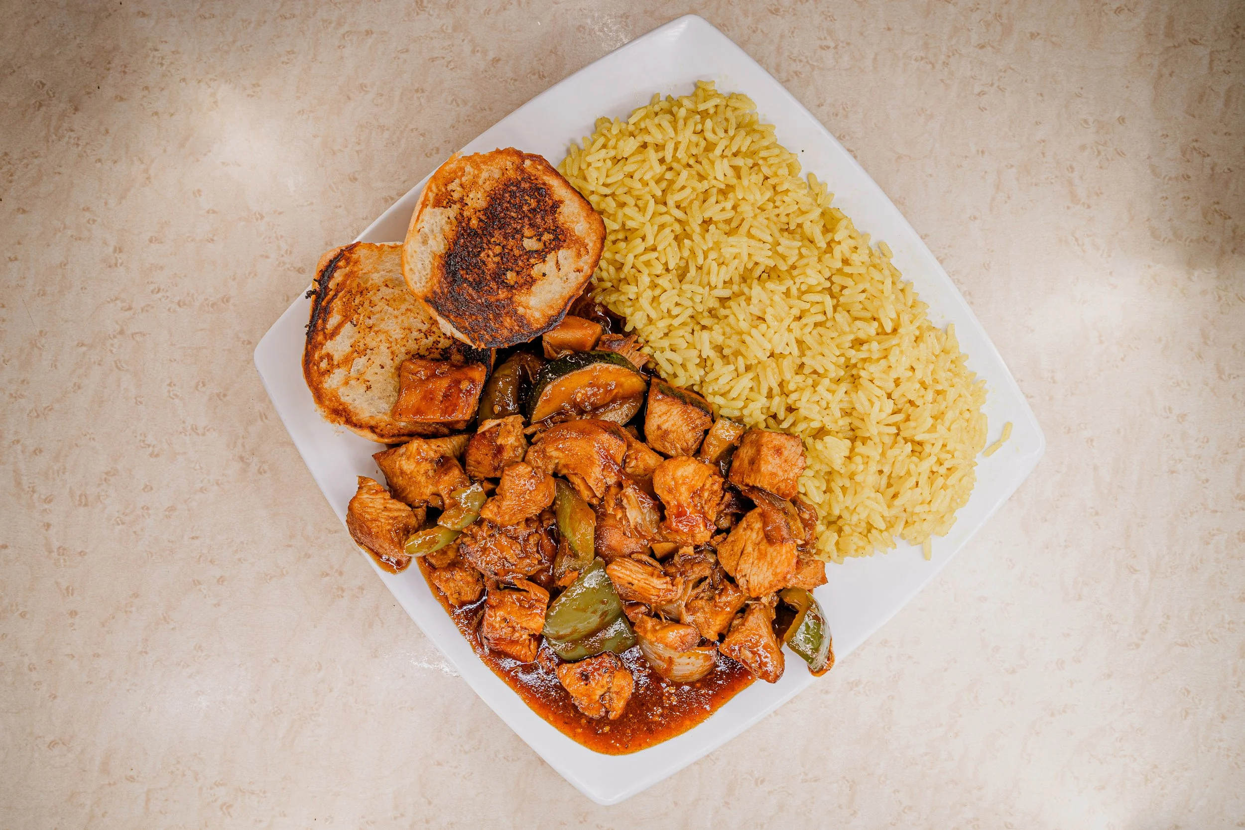 Plate of cooked rice, grilled bread, sautéed chicken and vegetables, and a portion of stir-fried chicken with vegetables.