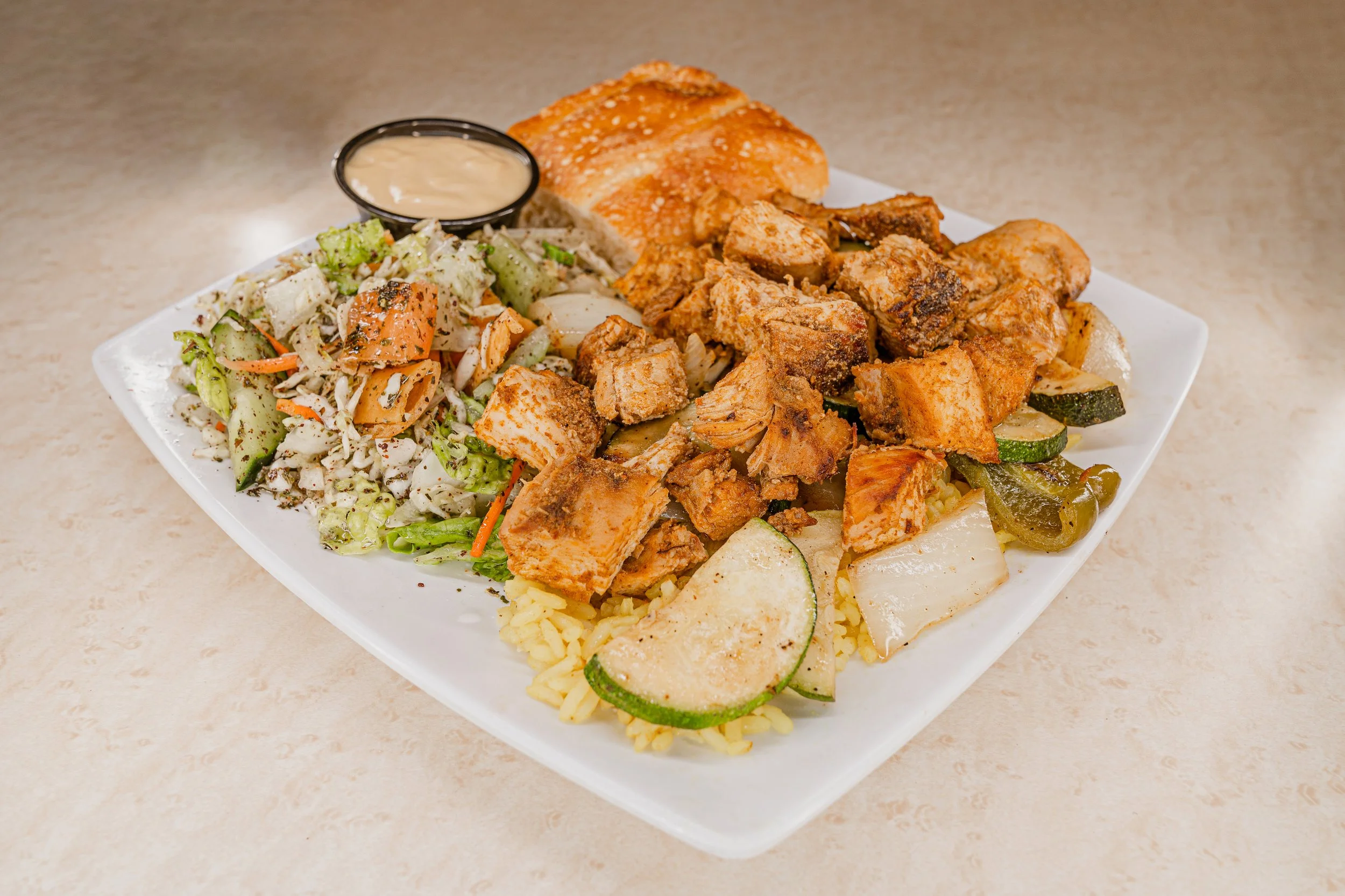 Plate with fried chicken, rice, salad, tortilla chips, and dipping sauce.