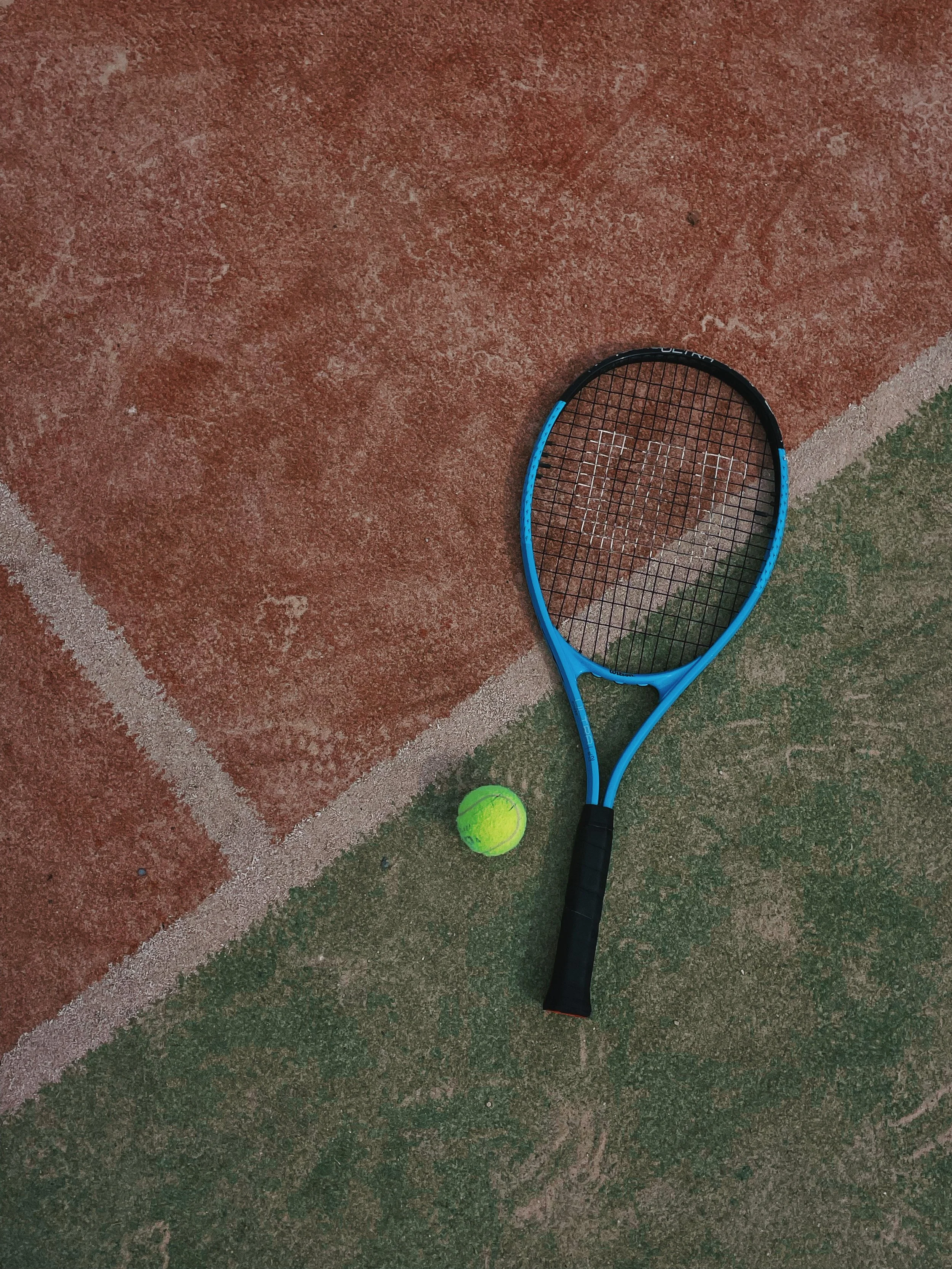 A tennis racket and a tennis ball on a tennis court.