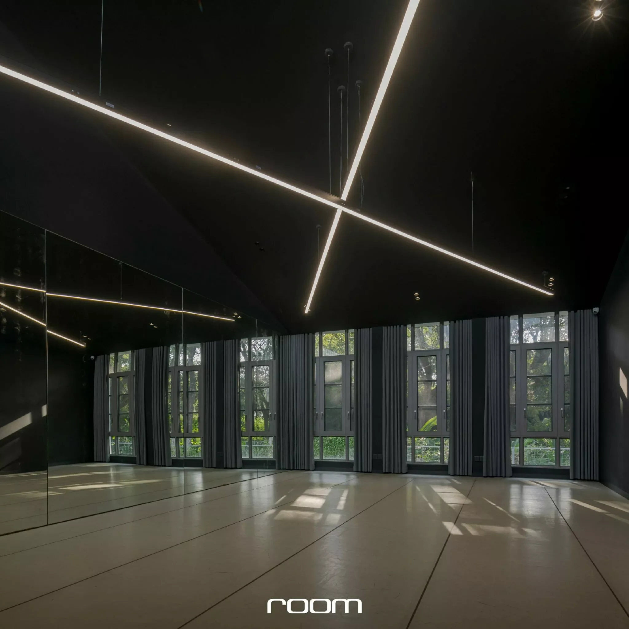 Modern interior with large windows, dark ceiling with linear lighting, and tiled flooring, possibly a lobby or atrium.