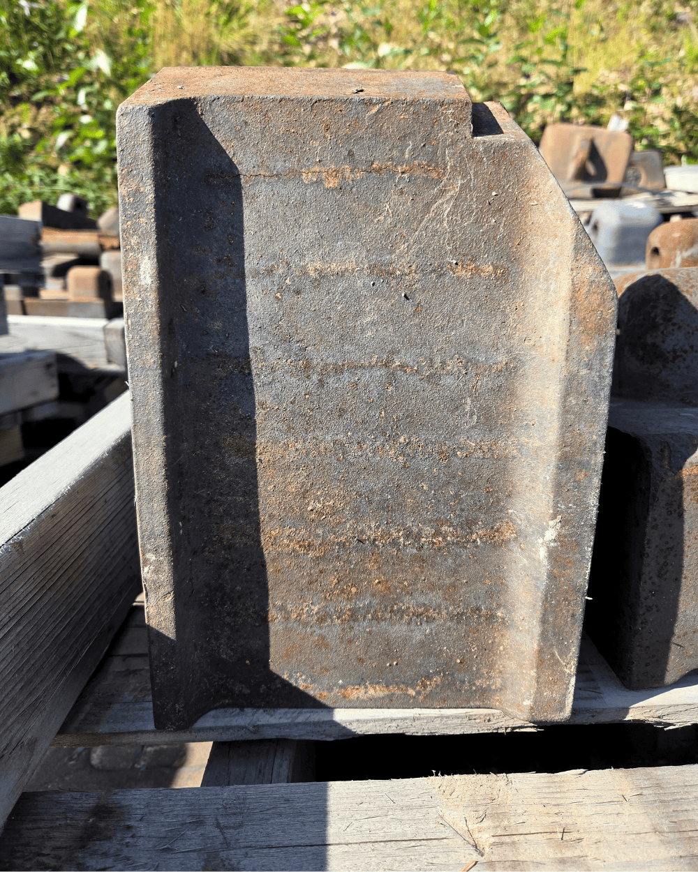 Large weathered cast-iron industrial component resting on a wooden pallet outdoors