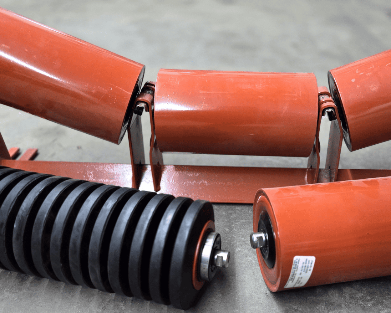 Red and black conveyor belt rollers on a concrete floor