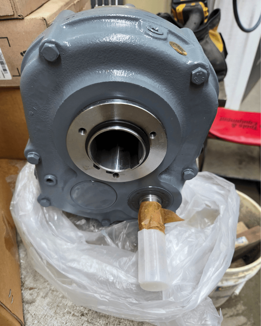 Close-up of a gray industrial gearbox housing with exposed shaft opening and capped lubrication port.