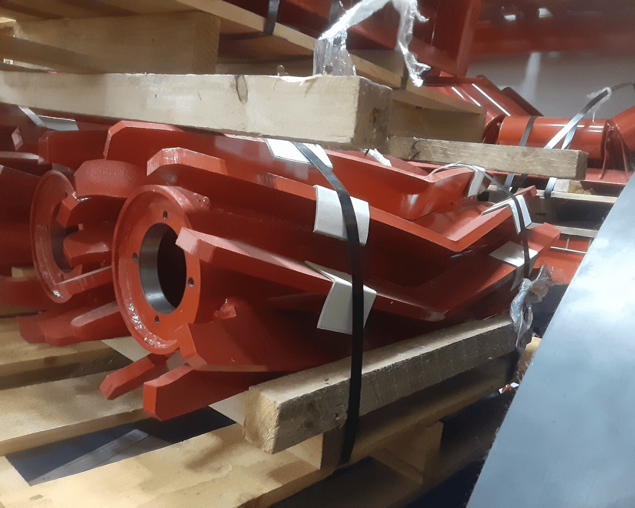 Red industrial metal components strapped to a wooden shipping pallet