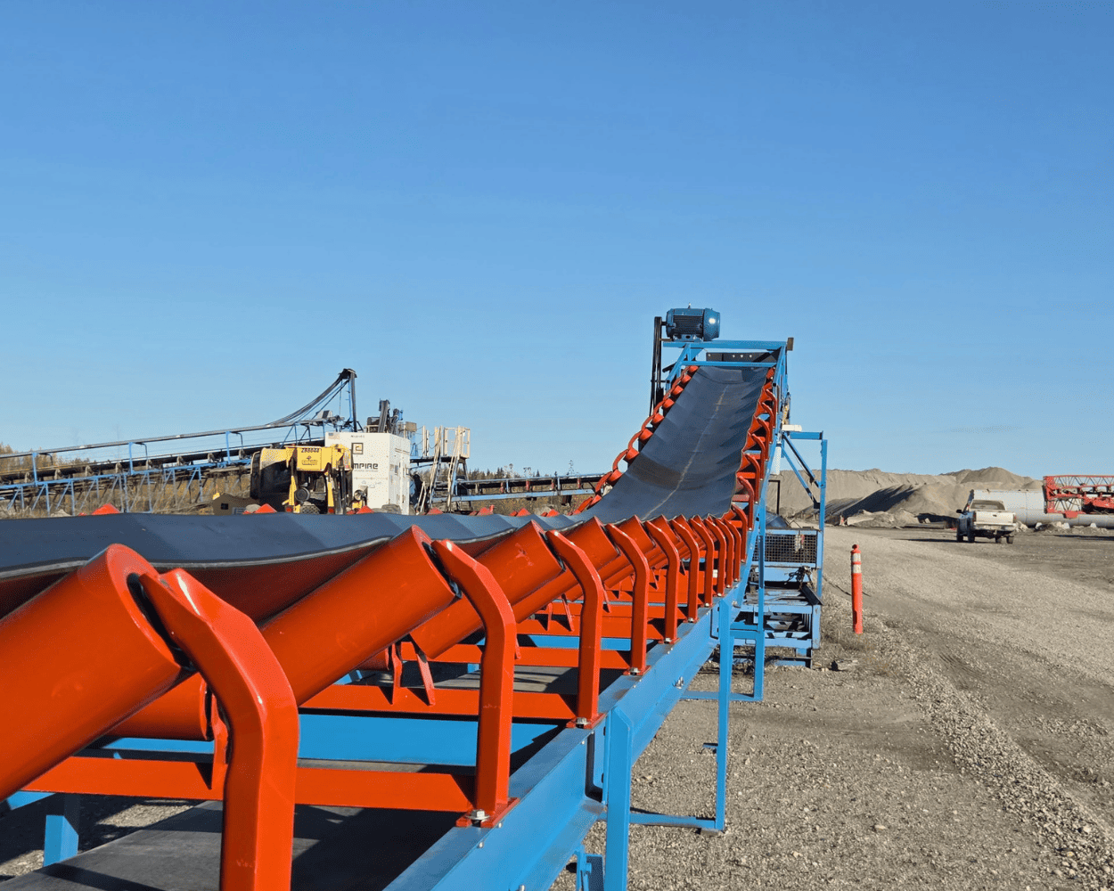 Industrial conveyor belt system at an aggregate quarry under a clear blue sky