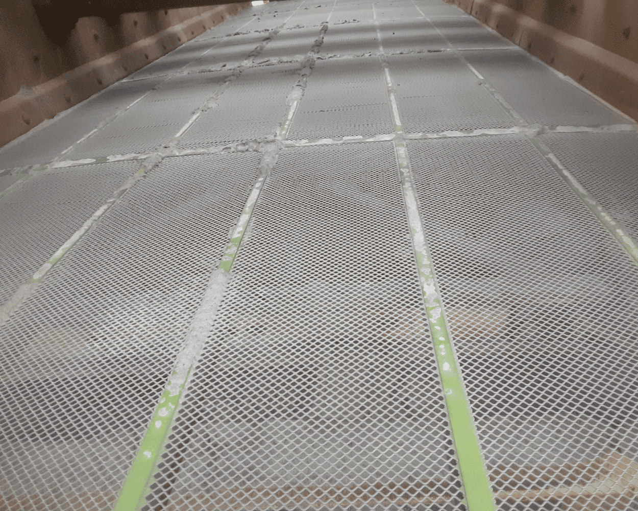 Close-up of a perforated metal walkway or platform inside a weathered industrial structure