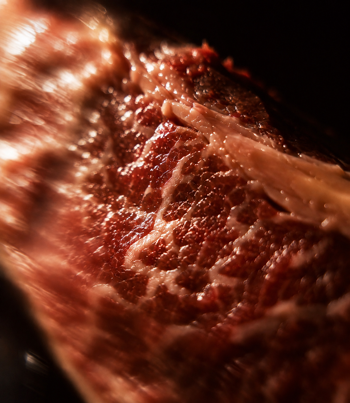 Close-up of raw beef steak showing marbling of fat and muscle fibers.