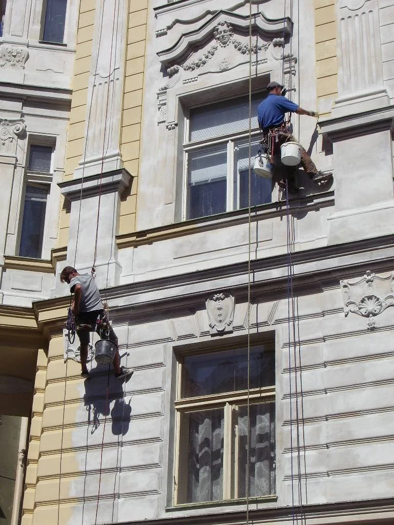 Two window washers working on the exterior of a historic building with ornate architectural details.