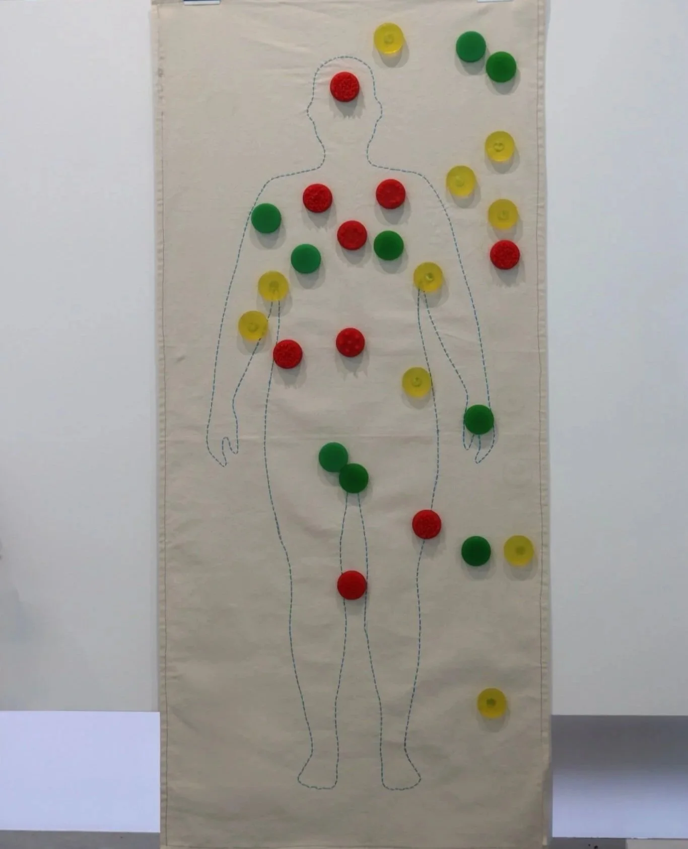 A large sheet of paper with an outline of a human body drawn in blue, covered with various colored circles in red, yellow, and green, arranged along the outline to teach consent.