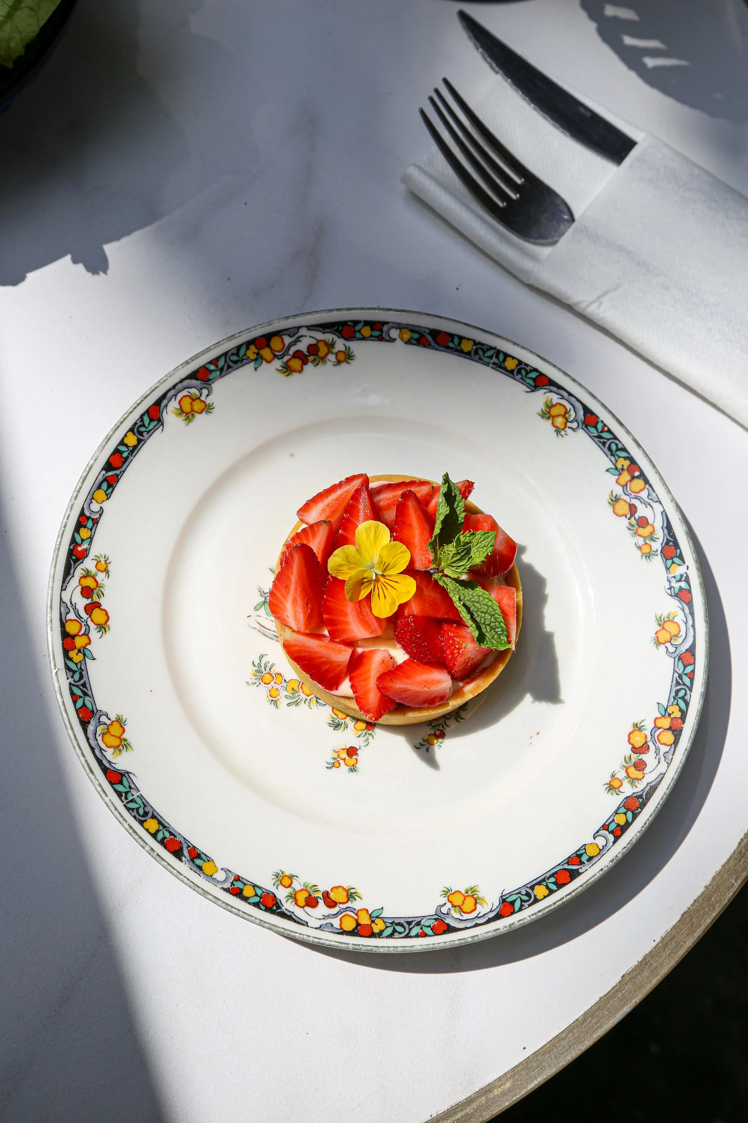 Une assiette décorée de fleurs avec un dessert aux fraises et à la menthe.