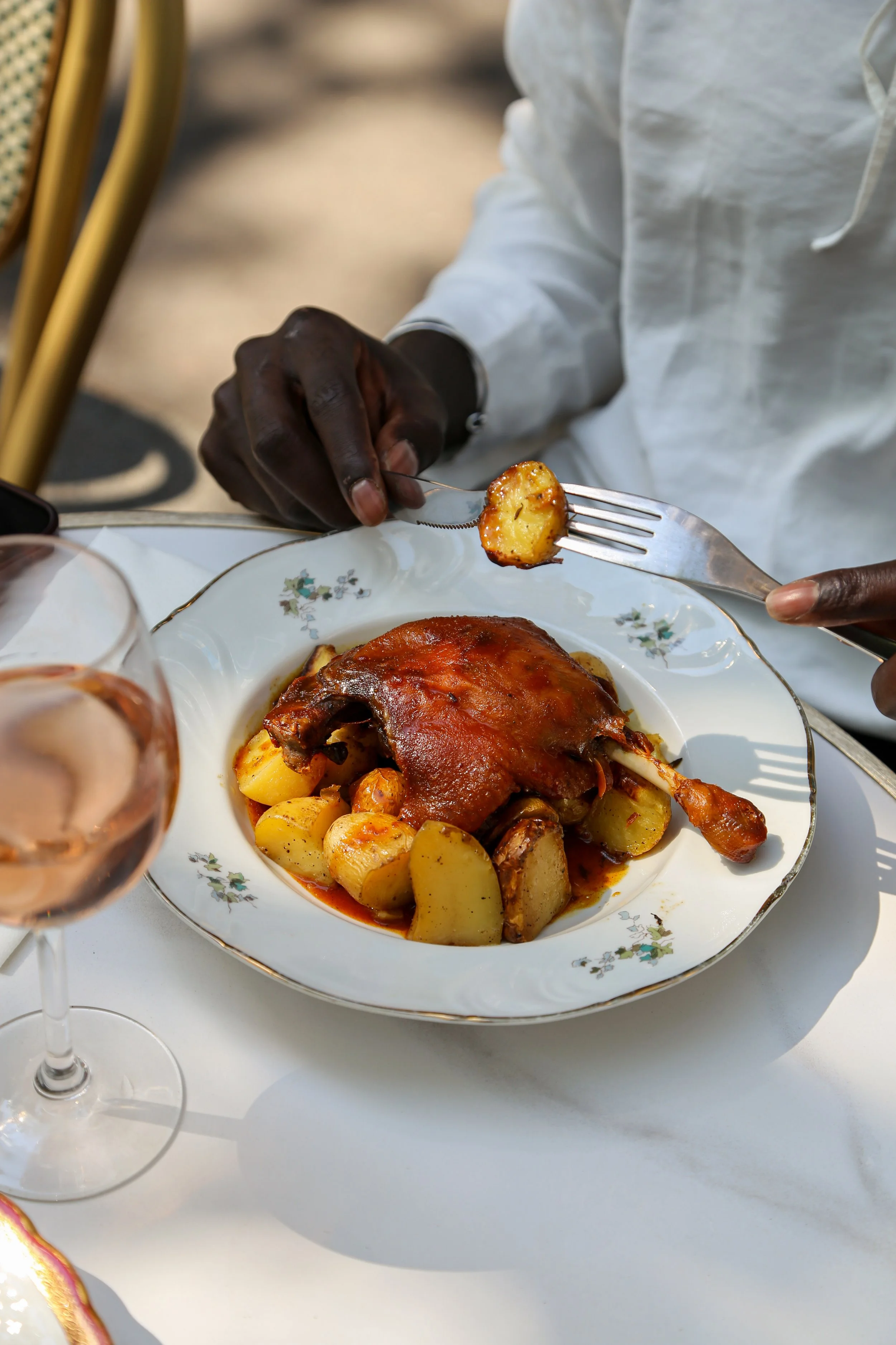 Assiette avec un plat de coq à la bière et pommes de terre, accompagnée d'un verre de vin rosé.