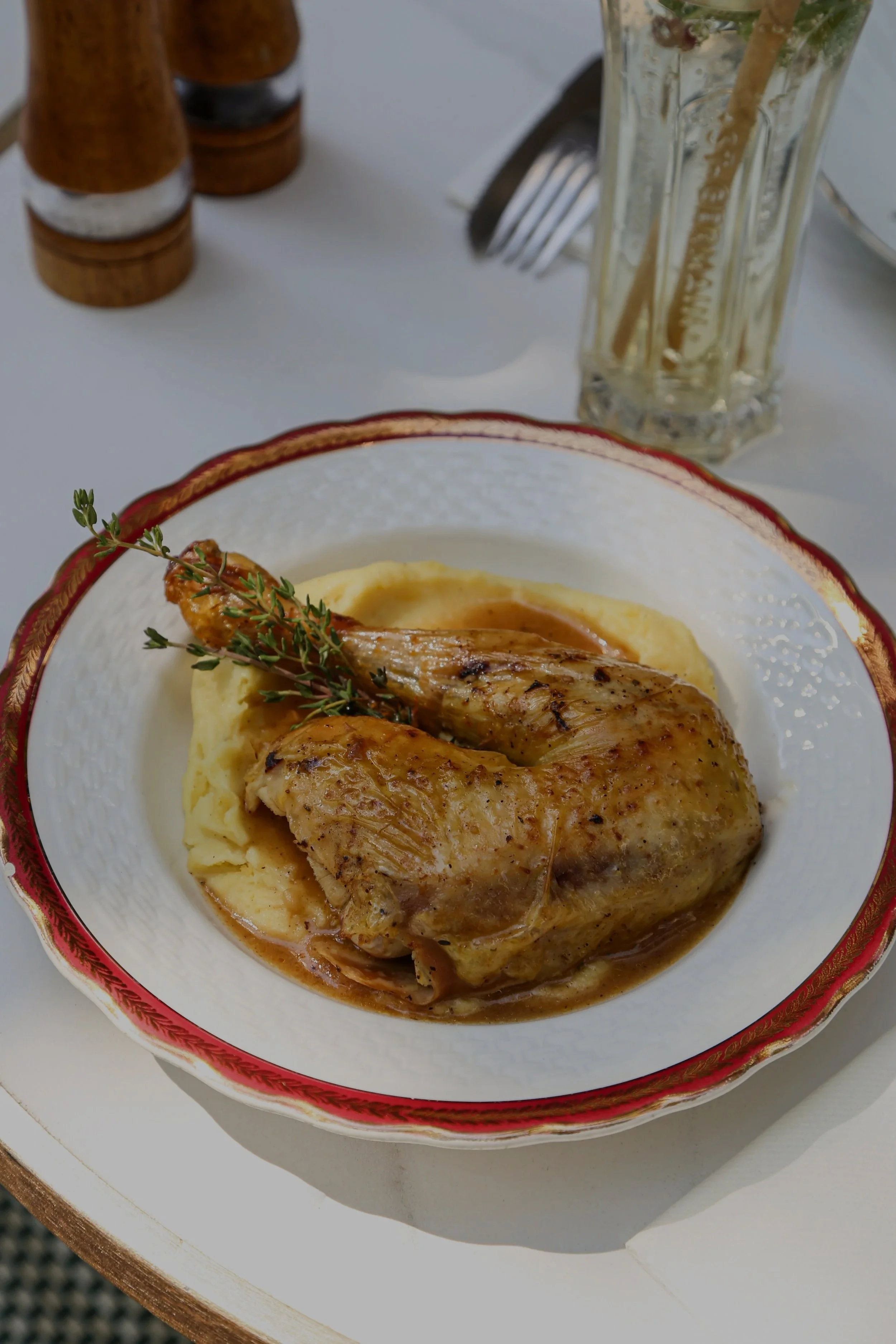 Poulet rôti servi avec purée de pommes de terre sur une assiette décorative, garnie de thym.