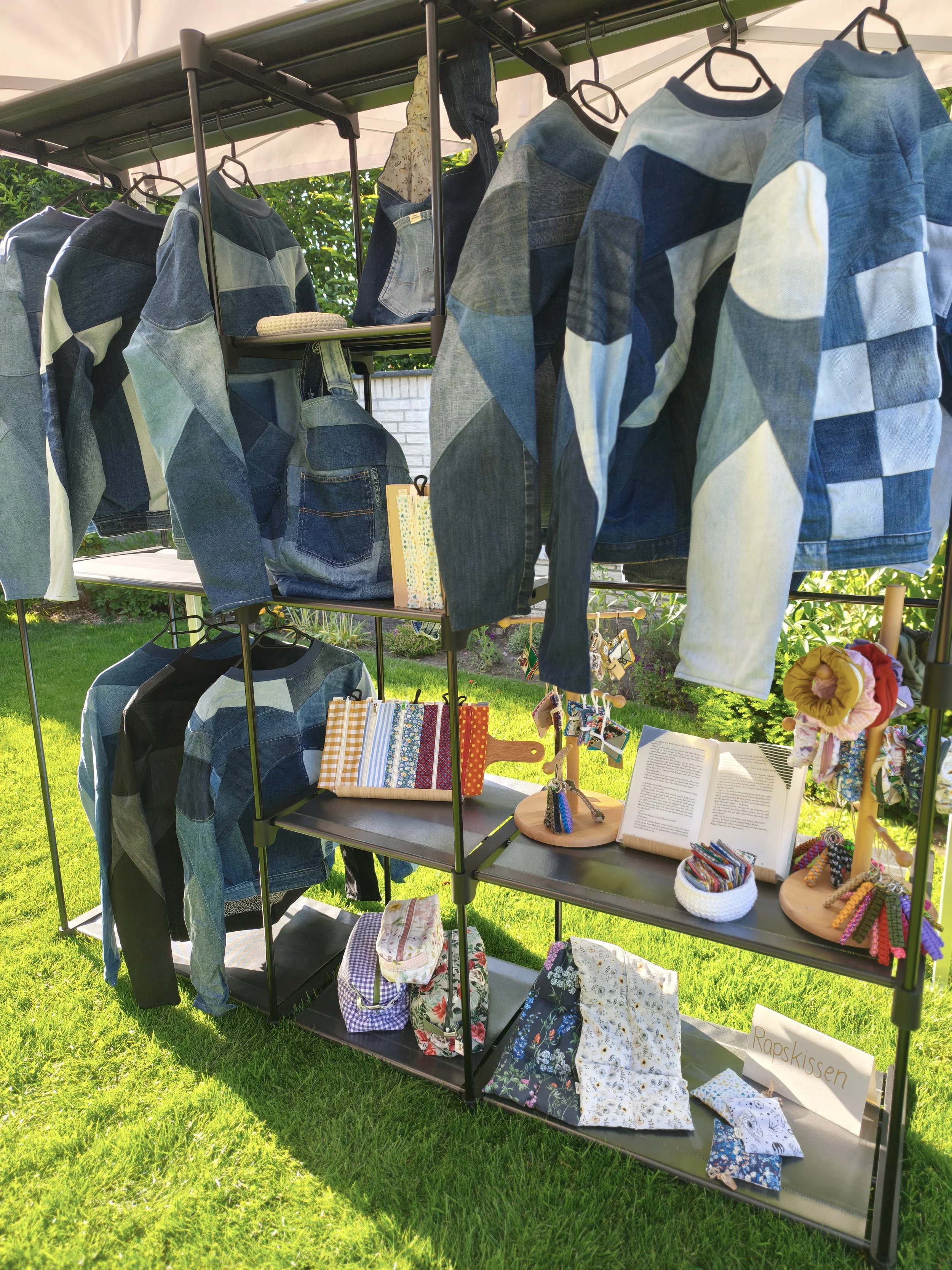 offenes Regal befüllt mit Anniroc Design Upcycling Jeansjacken und weiteren selbstgenähten Produkten