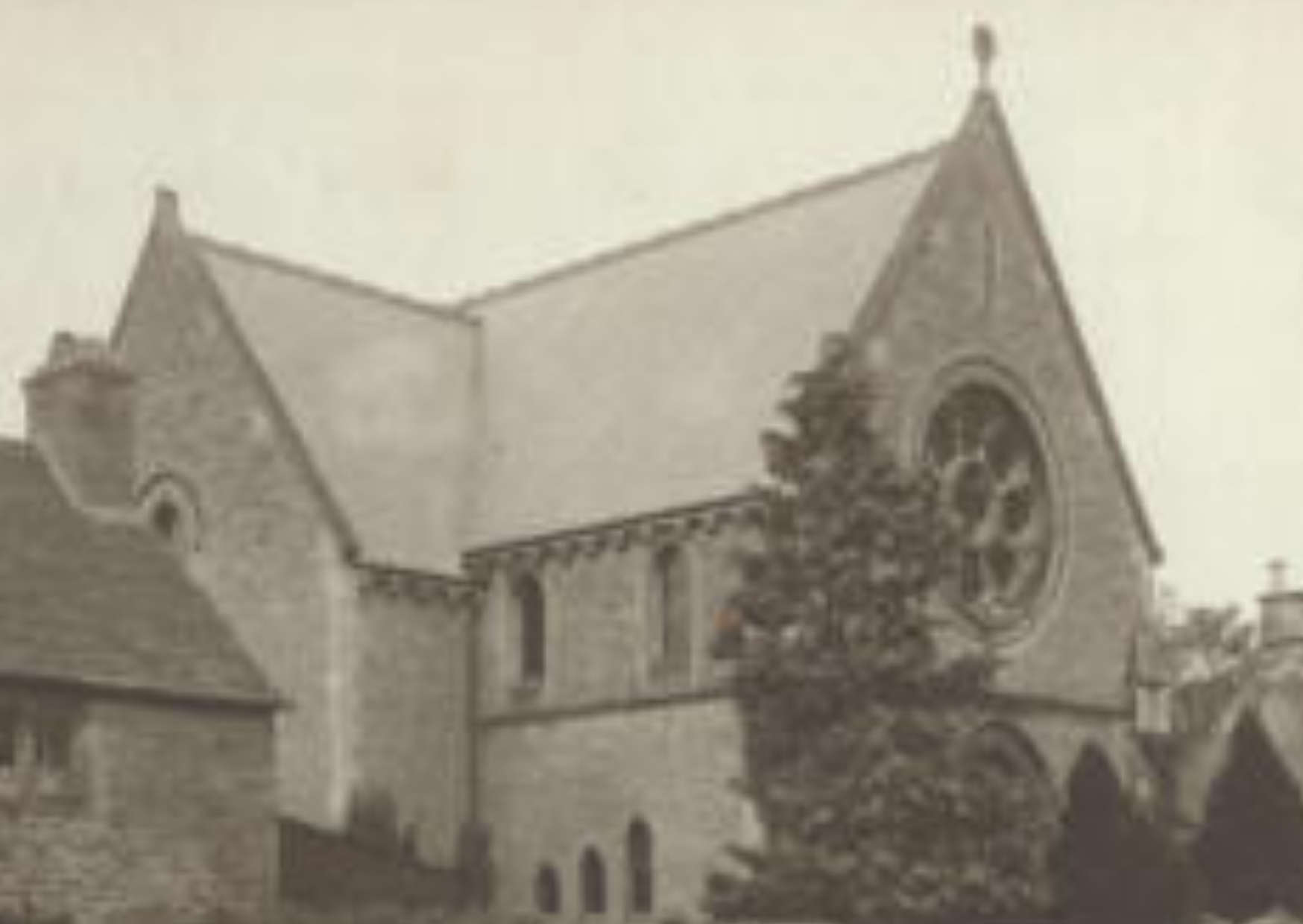 An old sepia-toned photograph showing a church with its steeple, and a large billboard structure in front of the church with unknown content.